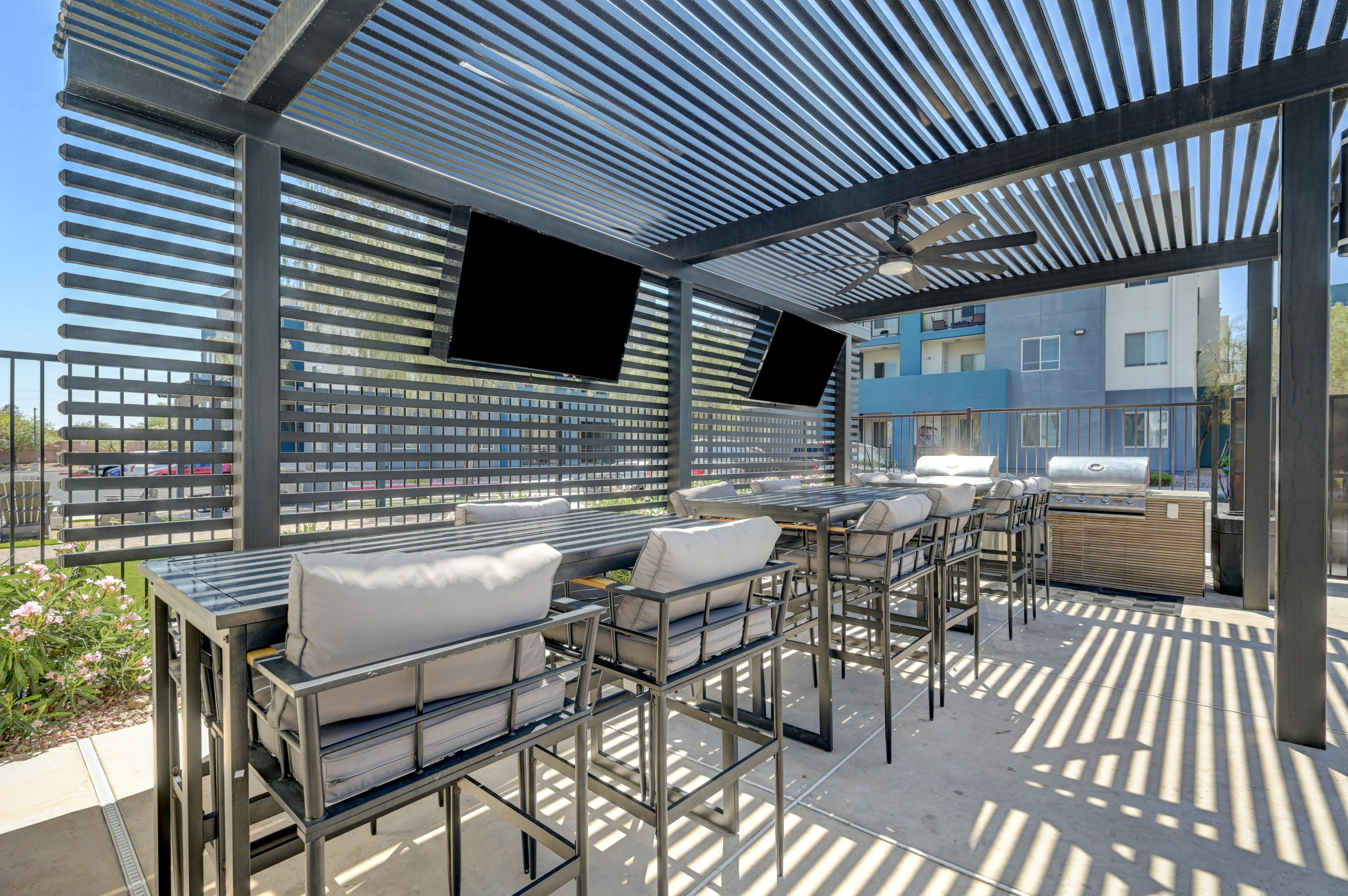 Chic outdoor lounge area with modern pergola, comfortable seating, and built-in grills, perfect for entertaining.