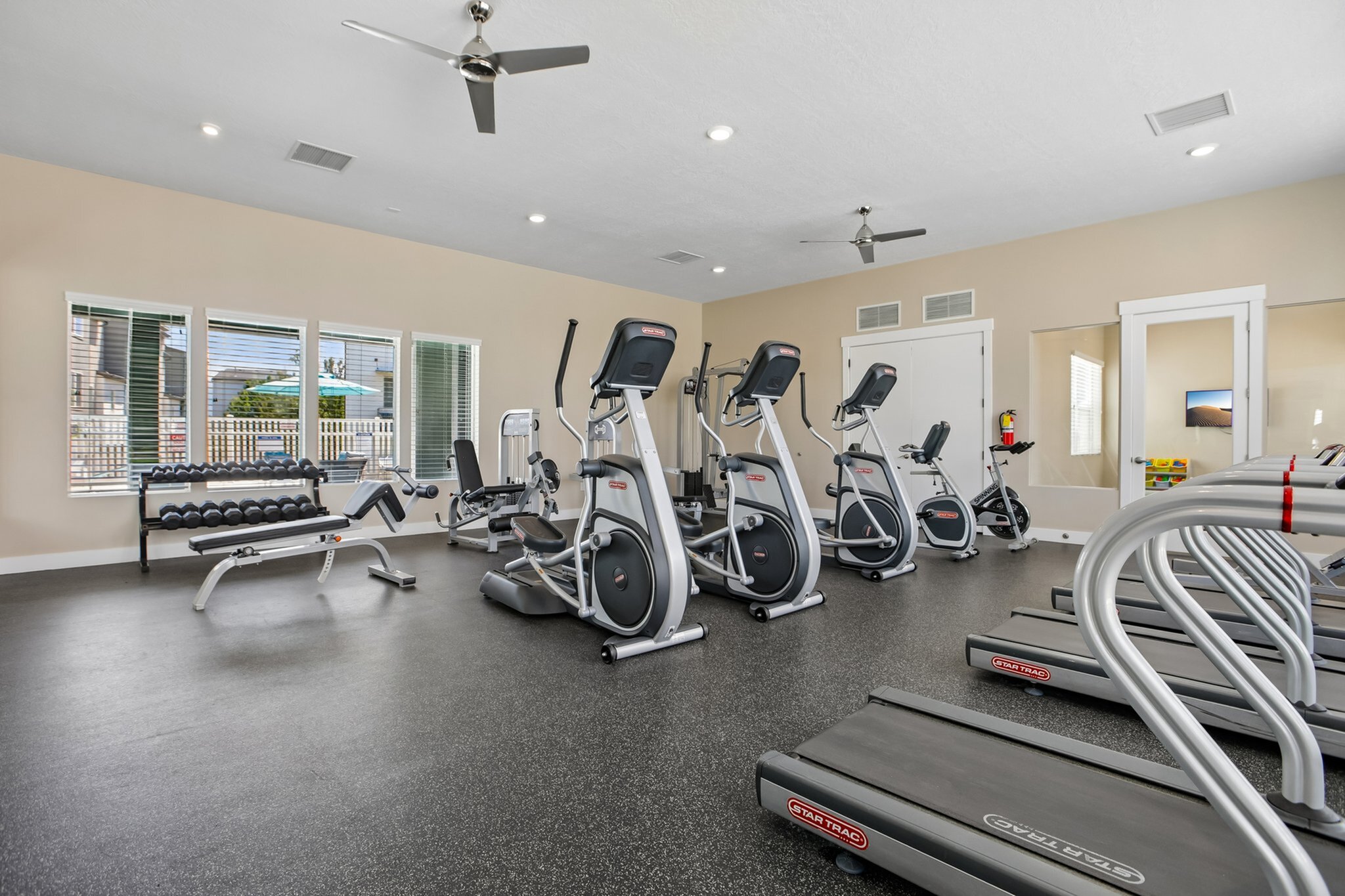 Bright and modern fitness center featuring state-of-the-art treadmills, ellipticals, and weightlifting equipment, perfect for an invigorating workout experience.