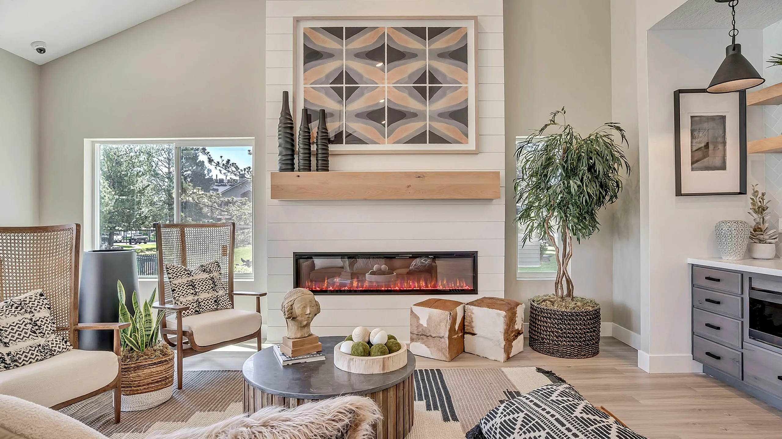 Chic clubhouse with modern electric fireplace, elegant decor, and cozy seating, enhanced by natural light and stylish furnishings.