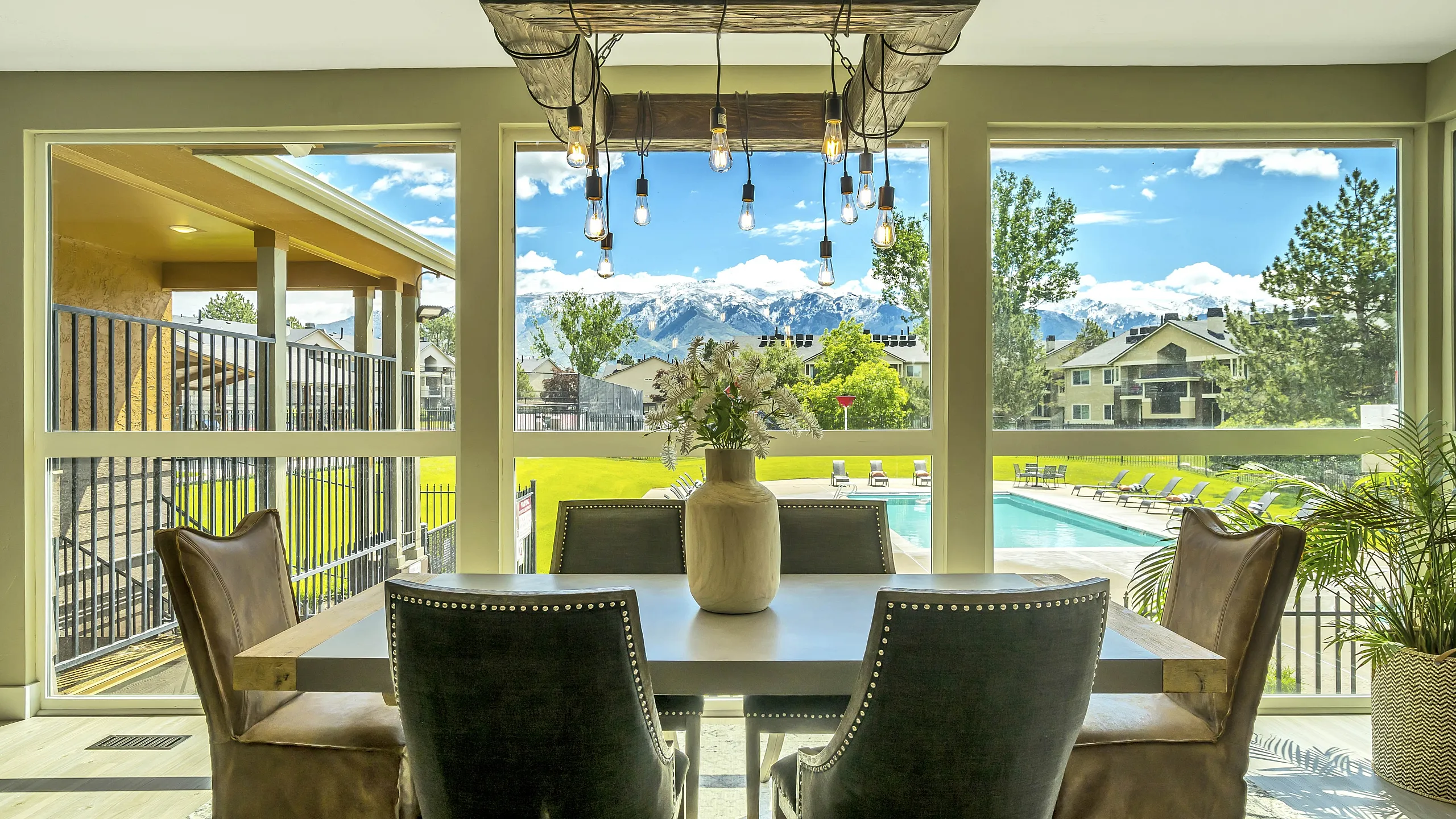 Bright dining area with stylish lighting, offering stunning views of a crystal-clear pool and majestic mountains, perfect for relaxation and entertaining.