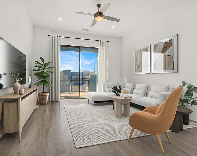 Modern living room with a cozy white sectional sofa, elegant decor, and a large TV. Bright natural light streams through the glass doors leading to a private balcony.