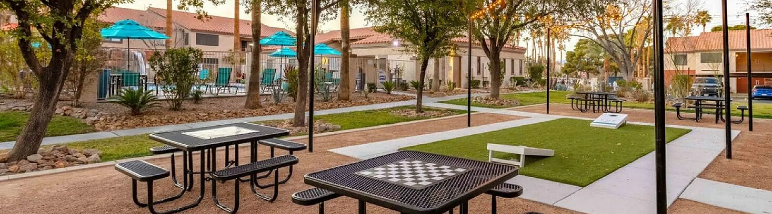 Charming outdoor communal area with string lights, picnic tables, and lush greenery, perfect for gatherings and relaxation.