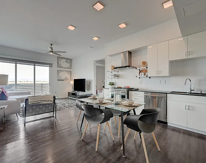 Modern open-concept living room and kitchen with sleek design, featuring large windows, elegant dining area, and cozy seating.