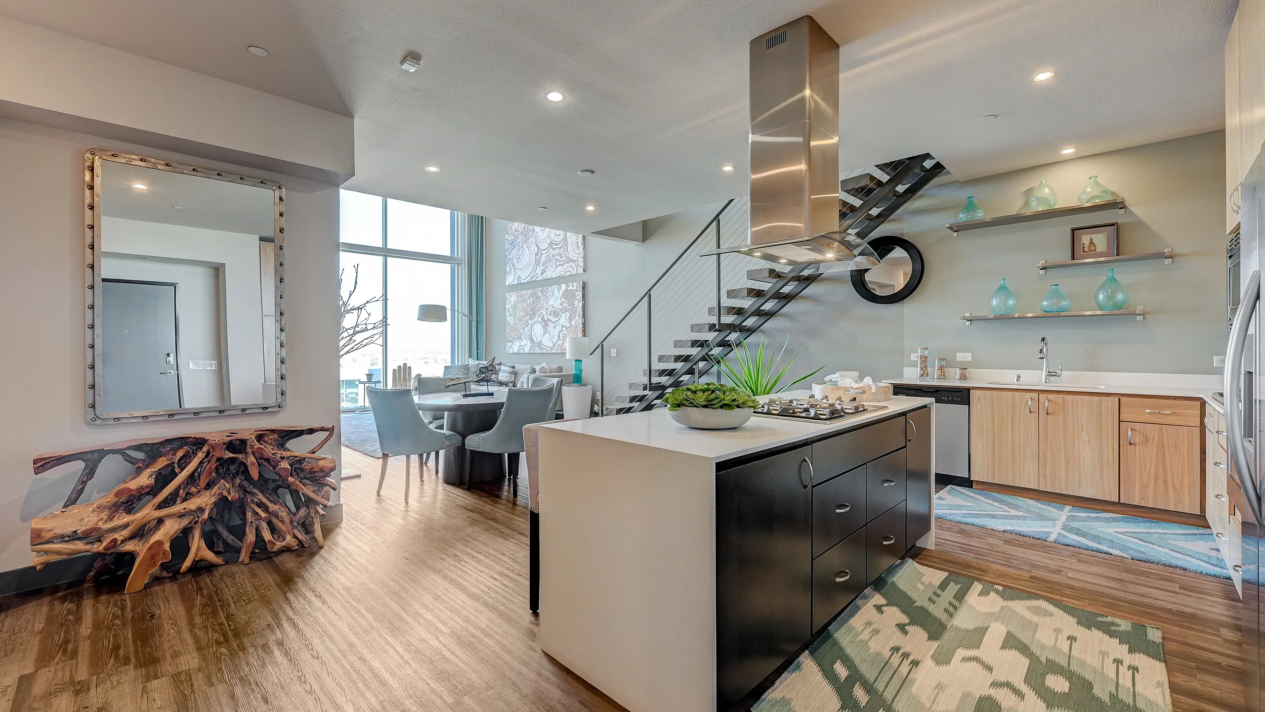 Modern loft apartment with a sleek kitchen, stylish dining area, and elegant staircase, featuring chic decor and ample natural light.
