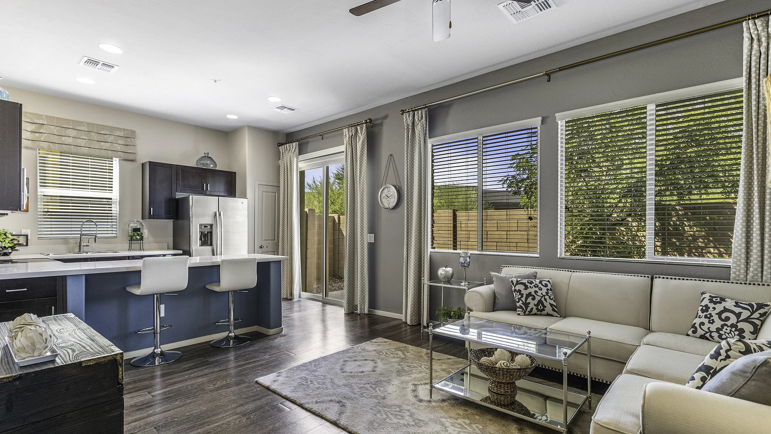 Modern open-concept living room and kitchen with sleek hardwood floors, stylish sectional sofa, and expansive windows offering abundant natural light.