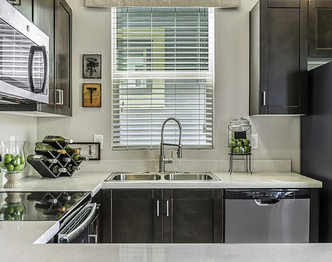 Modern kitchen with dark cabinets, stainless steel appliances, and a stylish countertop featuring a wine rack and decorative elements.