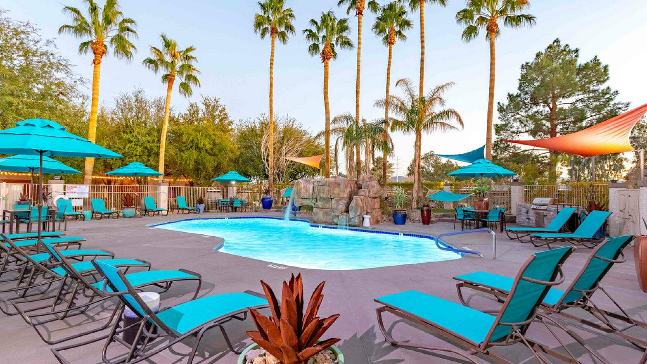 Luxurious outdoor pool area surrounded by stylish loungers and vibrant palm trees, creating a tropical oasis for relaxation.