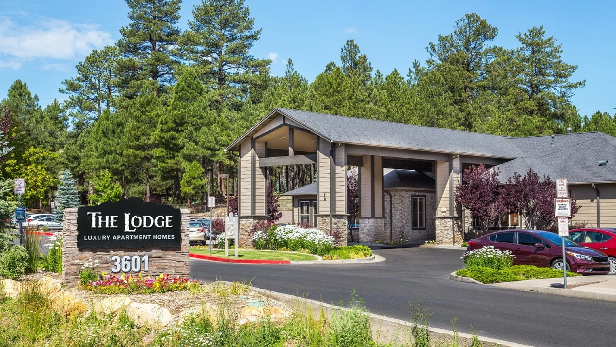 Charming Lodge apartment entrance surrounded by lush greenery and vibrant landscaping, offering luxury living amidst serene nature views.