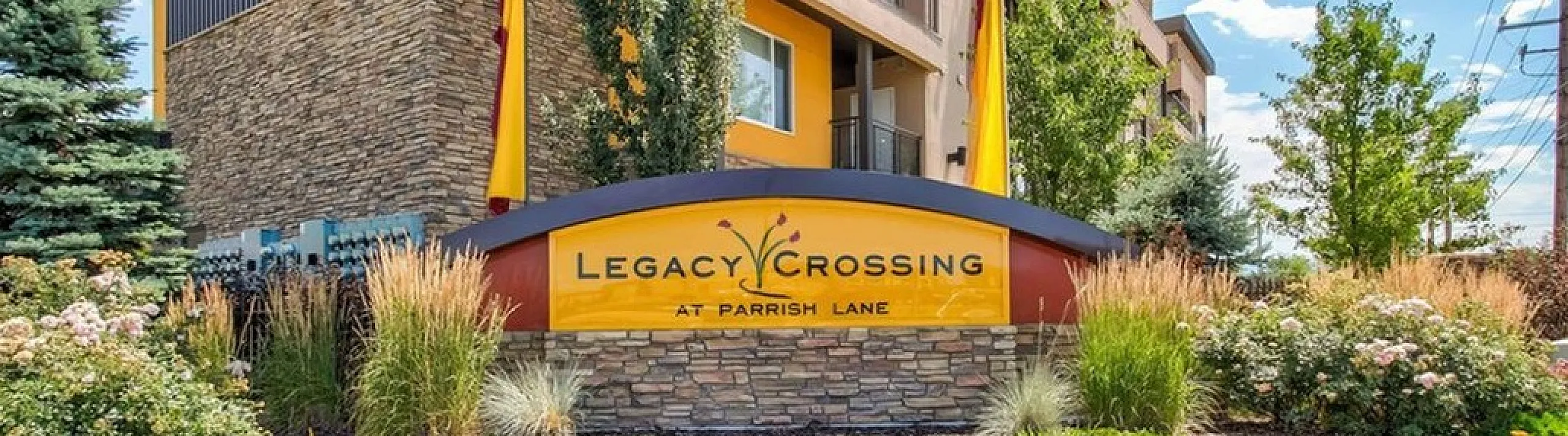 Modern apartment complex showcasing elegant architecture at Legacy Crossing, surrounded by lush landscaping and vibrant gardens.
