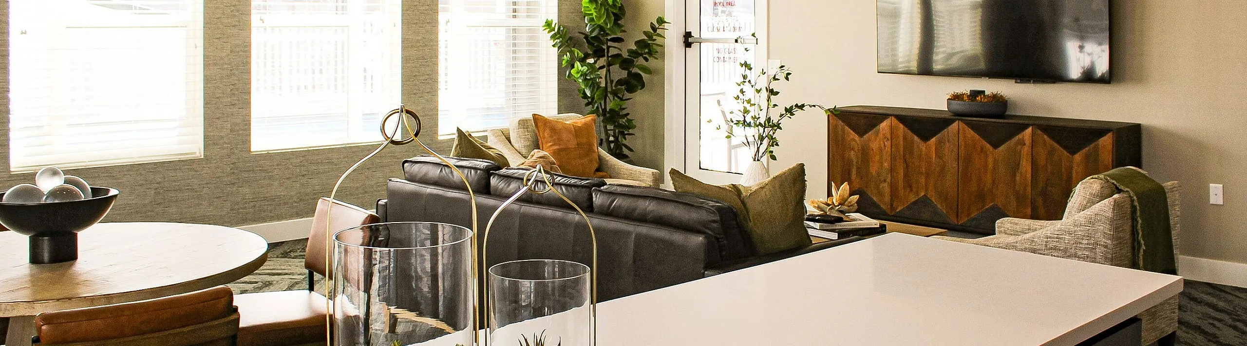 Modern open-concept living room with stylish decor, featuring a cozy seating area, elegant lighting, and a chic kitchen island with ornamental plants.
