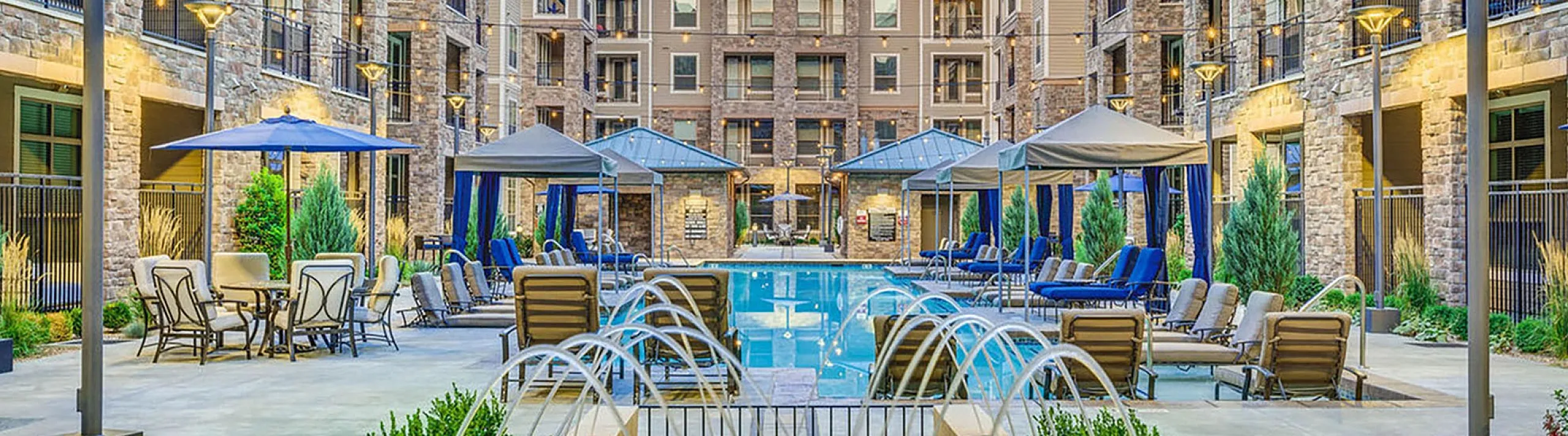 Bright, luxurious courtyard with a sparkling pool, elegant fountains, and comfortable lounging areas surrounded by modern multi-story apartments.