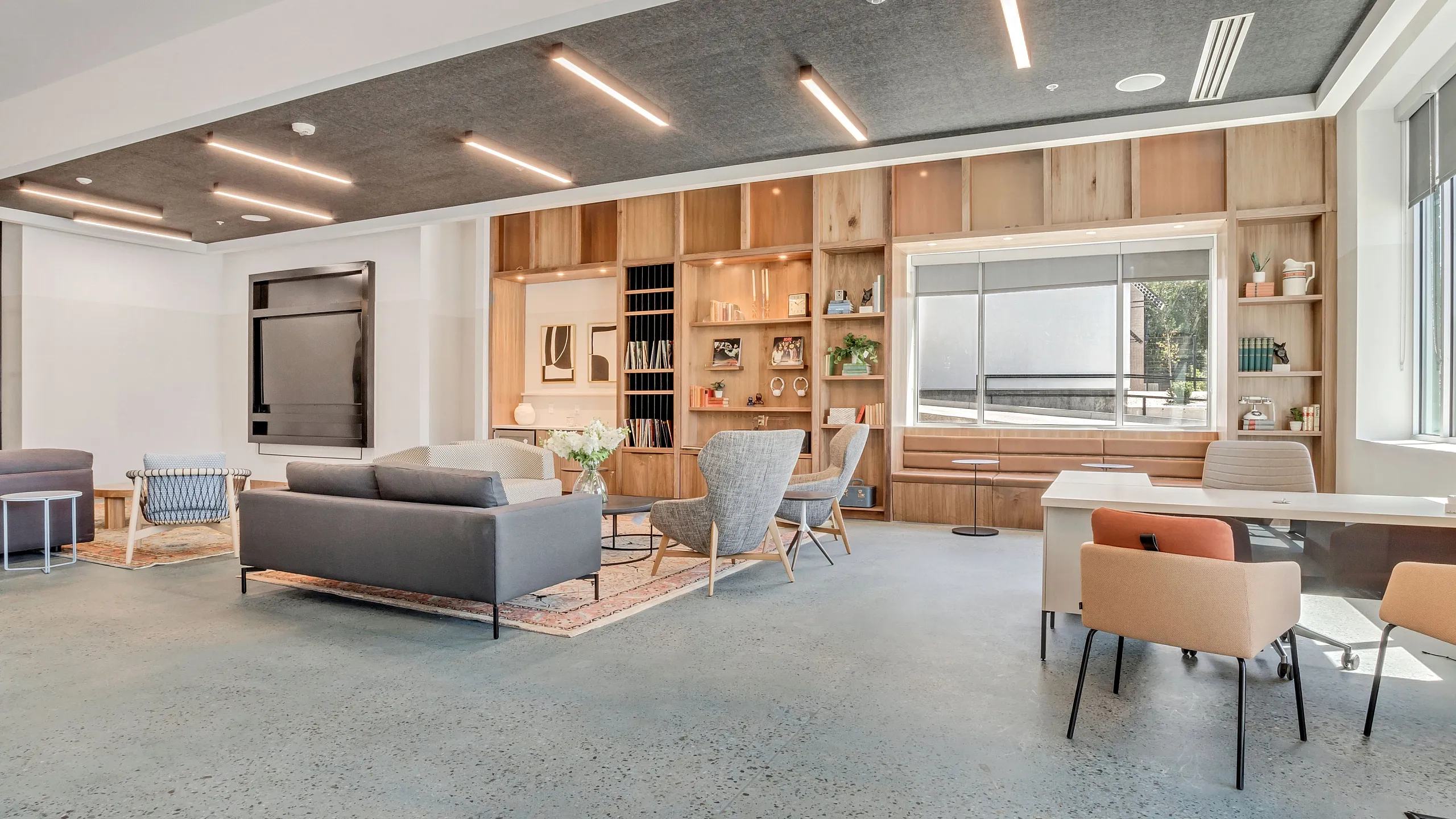 Modern and spacious living area with stylish furniture, a sleek entertainment unit, and abundant natural light from large windows.