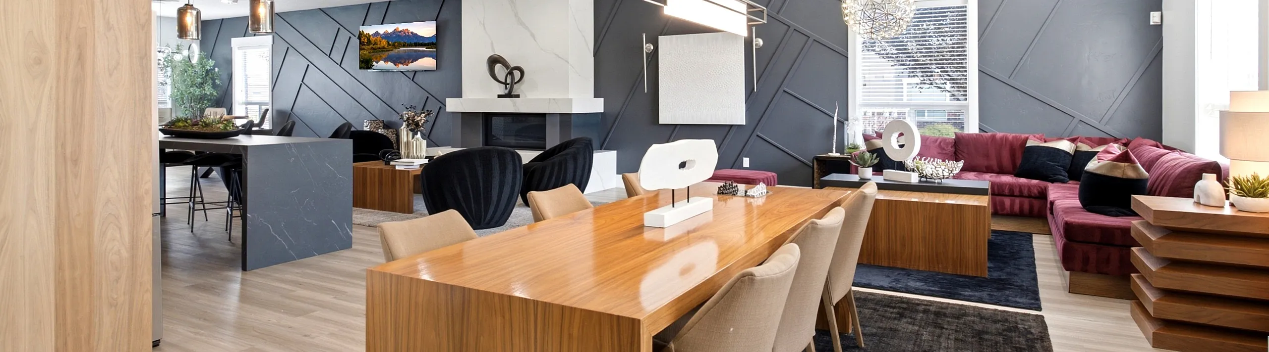 Elegantly designed open-concept living and dining area featuring modern furnishings, a sleek wood dining table, and stylish lighting fixtures, accented by a vibrant red corner sofa and geometric wall art.