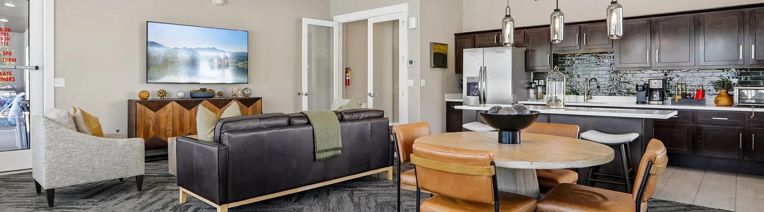Modern open-concept living space featuring elegant lighting, a stylish dining area, and a sleek kitchen with dark cabinetry.
