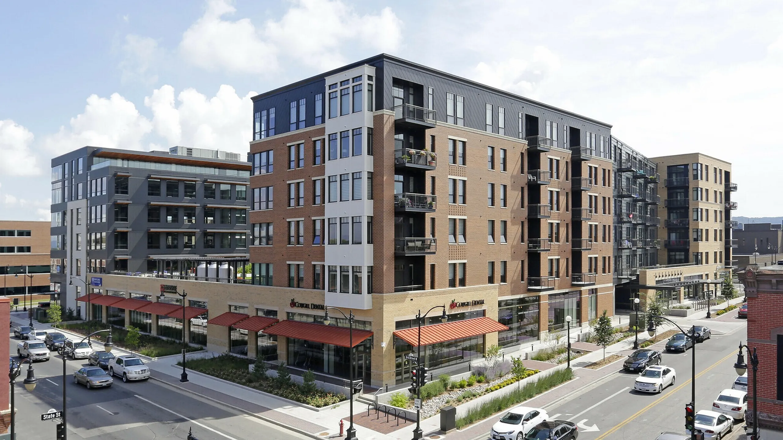 Modern urban apartment complex with sleek design and retail spaces at street level.