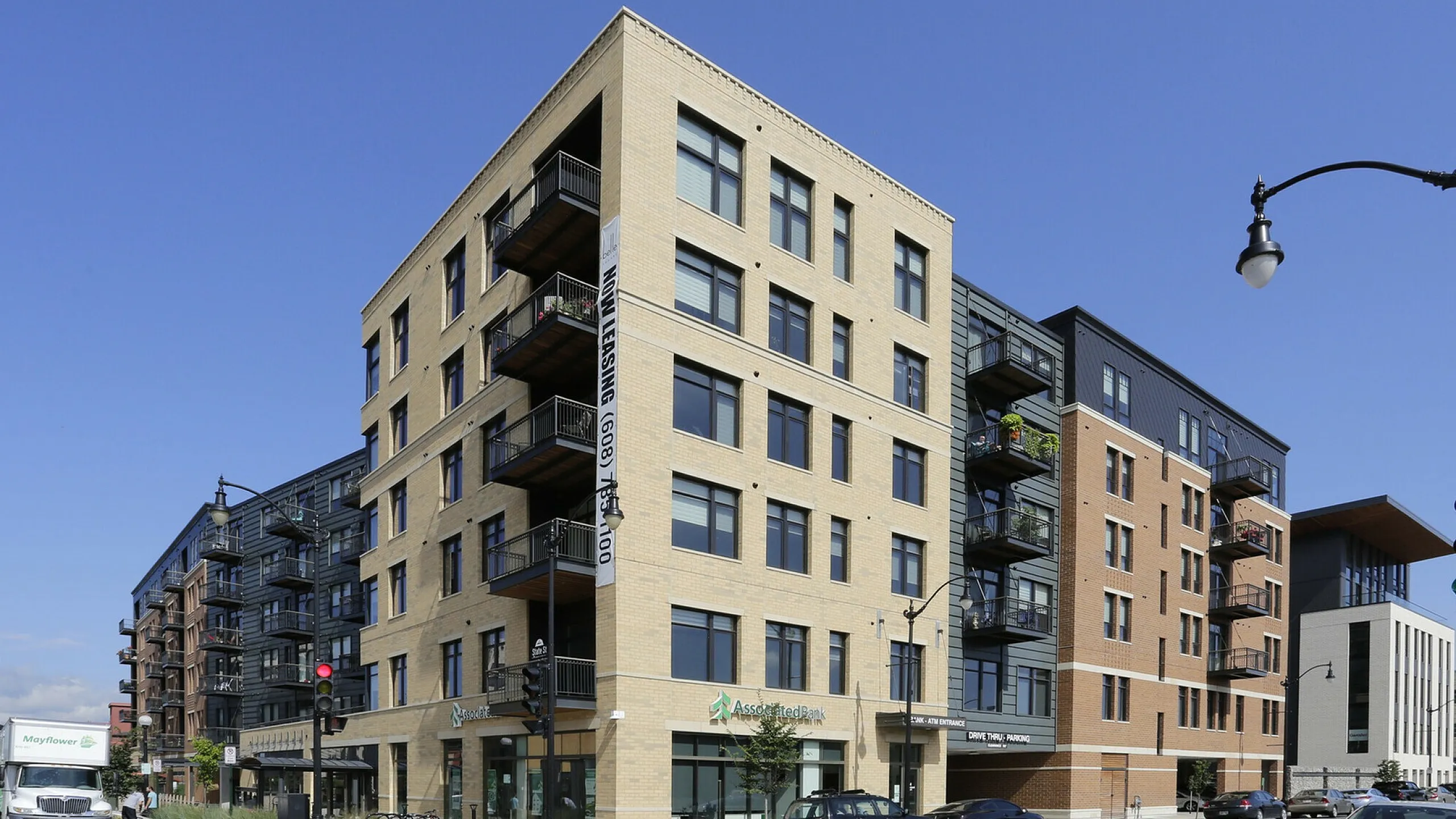 Contemporary multi-story apartment building with balconies and street-facing retail spaces.