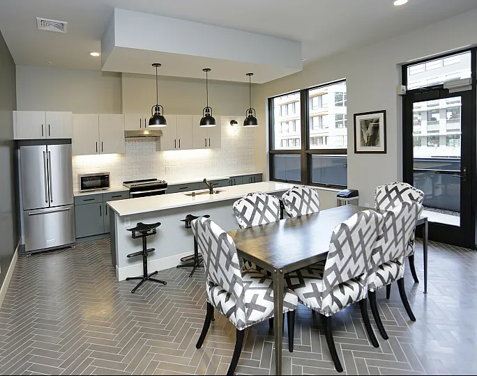 Stylish kitchen with stainless steel appliances, modern pendant lighting, and a sleek dining table in an urban apartment.