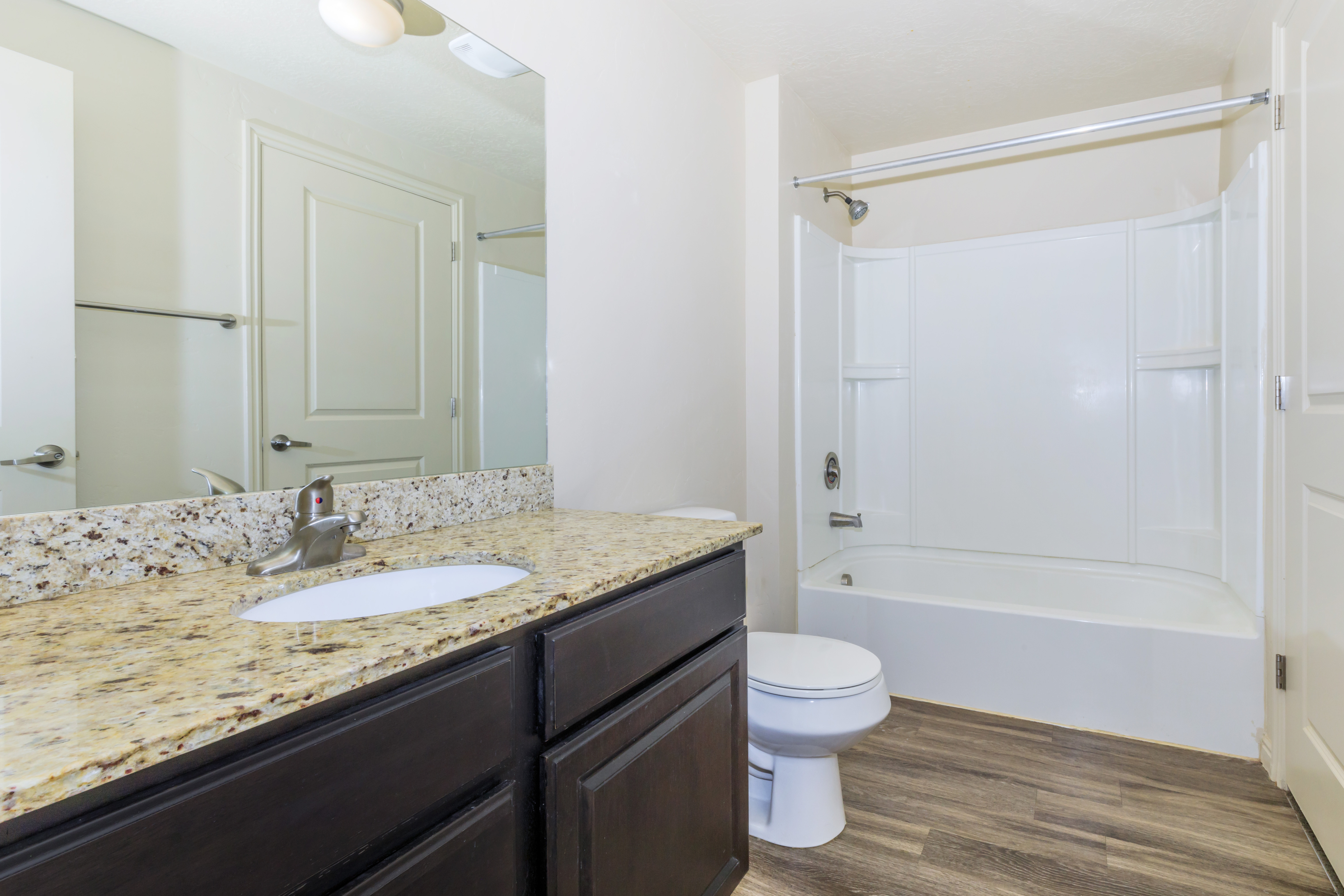 Elegant bathroom featuring a sleek granite countertop, modern fixtures, and a spacious bathtub for ultimate relaxation.