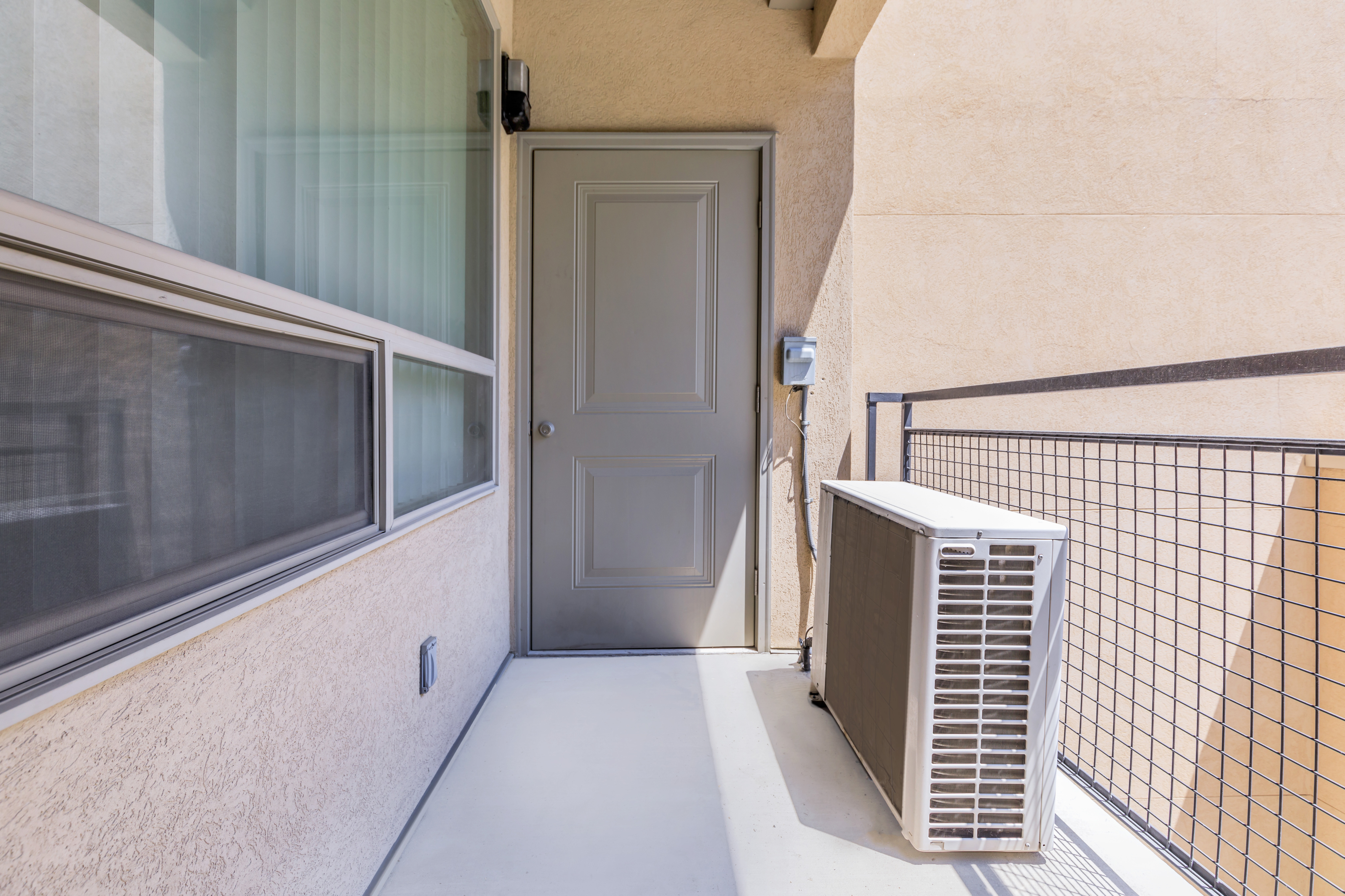 Modern apartment balcony with sleek air conditioning unit and large window, offering a stylish exterior view.