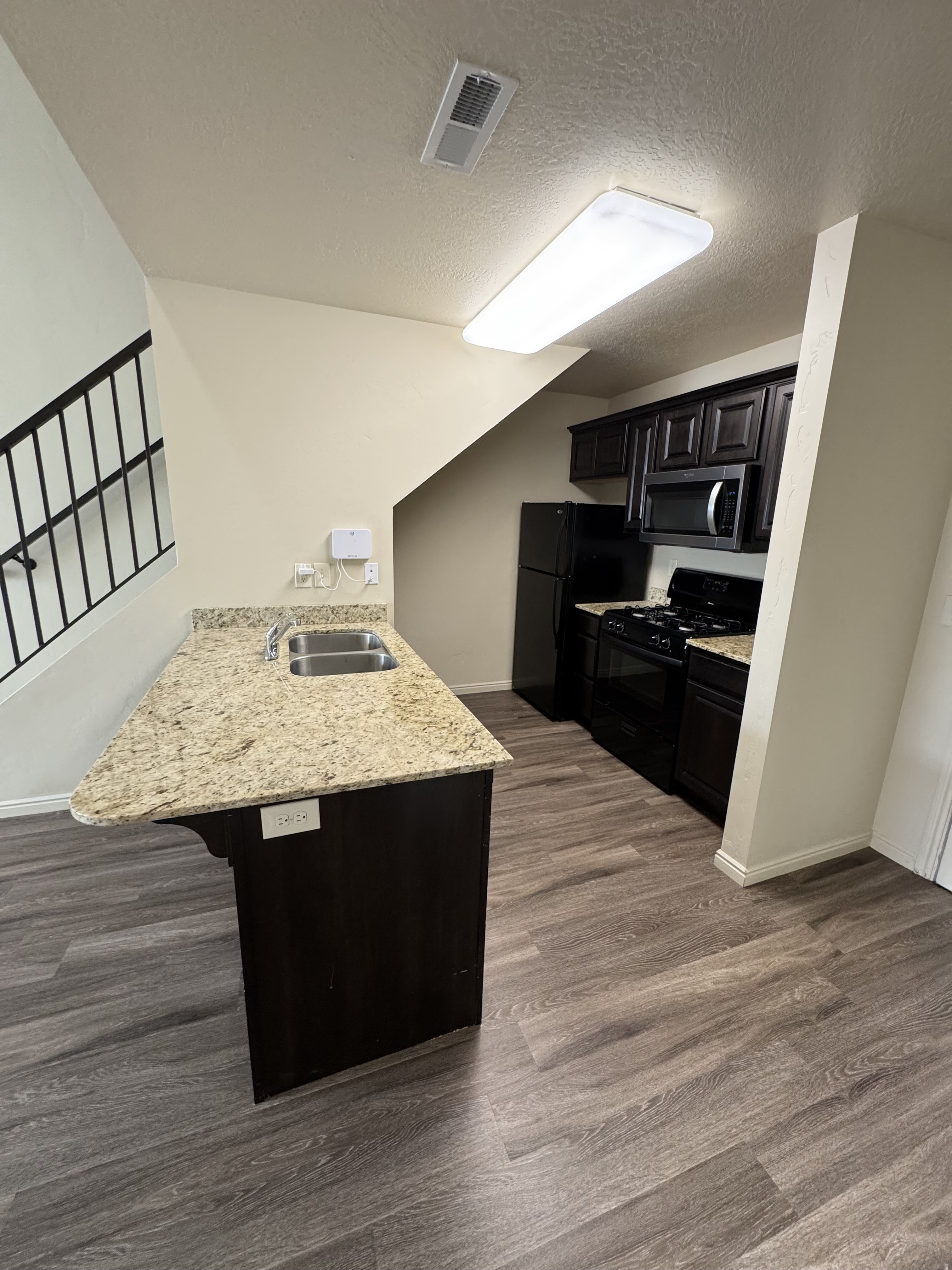 Modern kitchen with granite countertops, dark wood cabinets, and sleek stainless steel appliances, perfect for a stylish home.