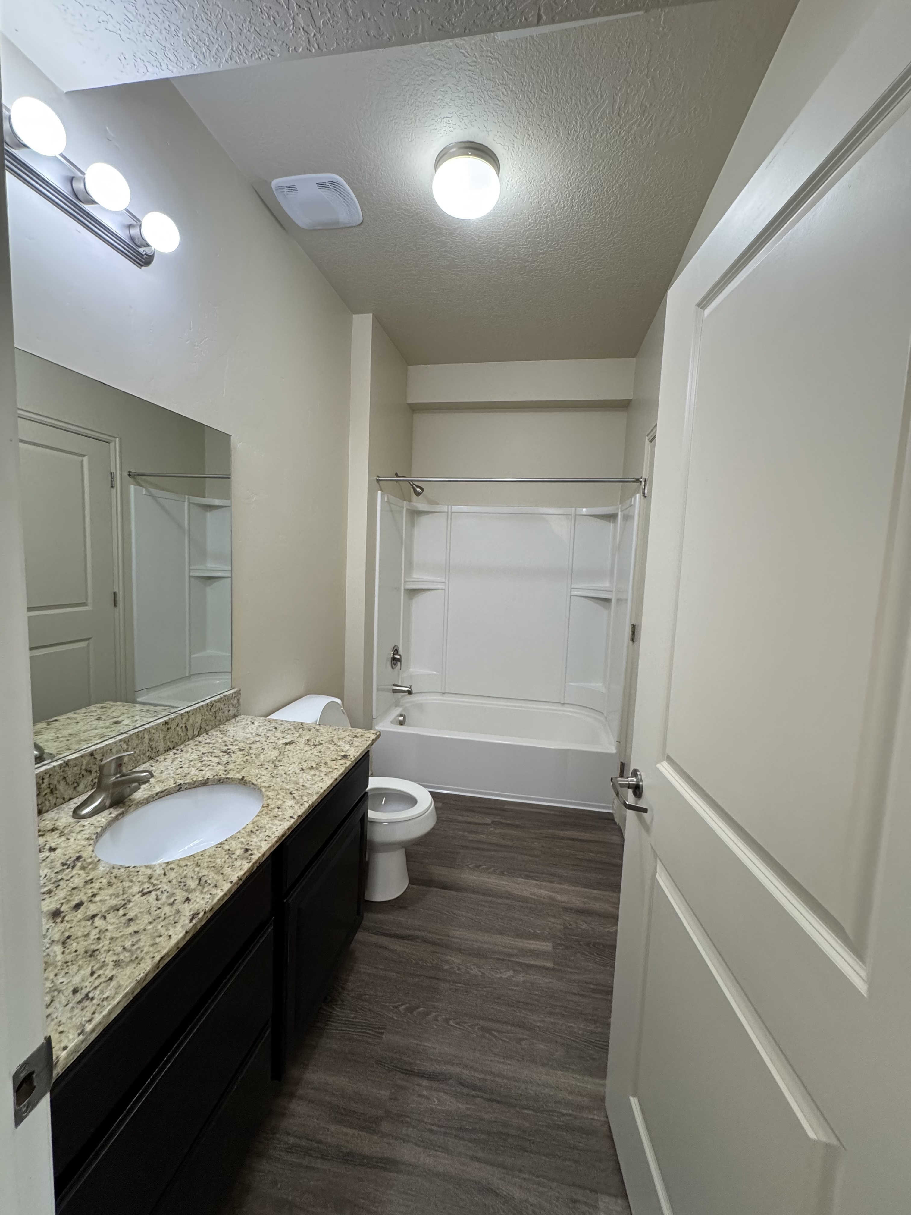 Modern bathroom with elegant granite countertops, sleek dark cabinets, and a classic bathtub.