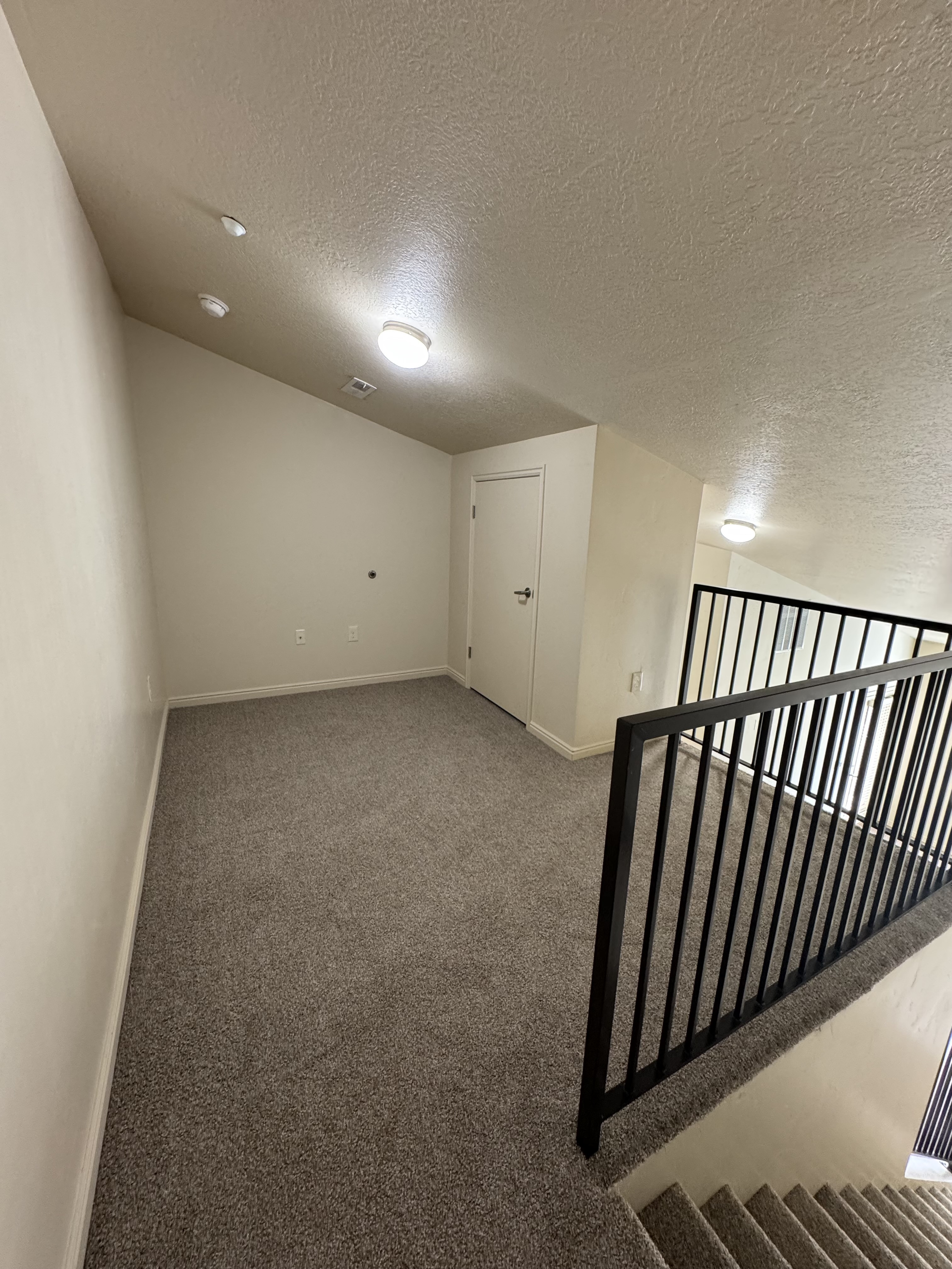 Chic loft space with plush carpet and modern railing overlooking stairs, perfect for a cozy living area.