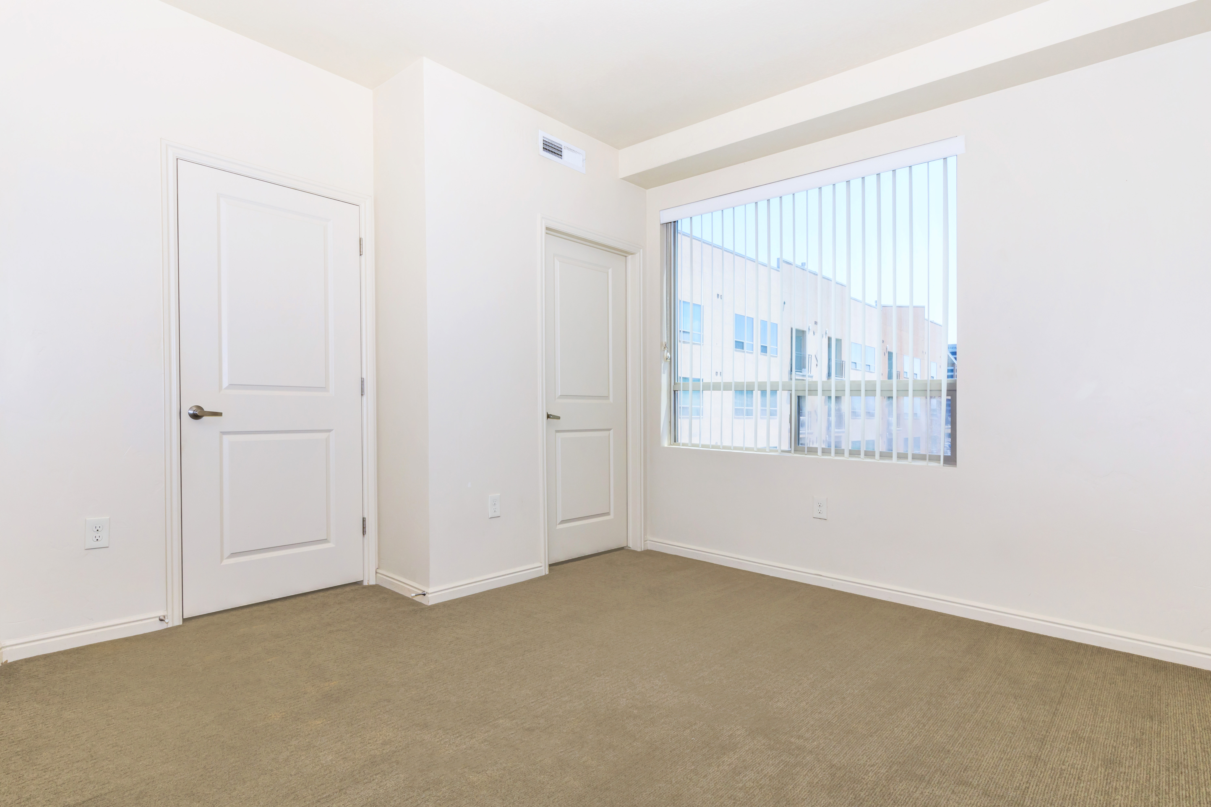 Bright and airy room with large window and modern neutral walls, highlighting spacious potential.