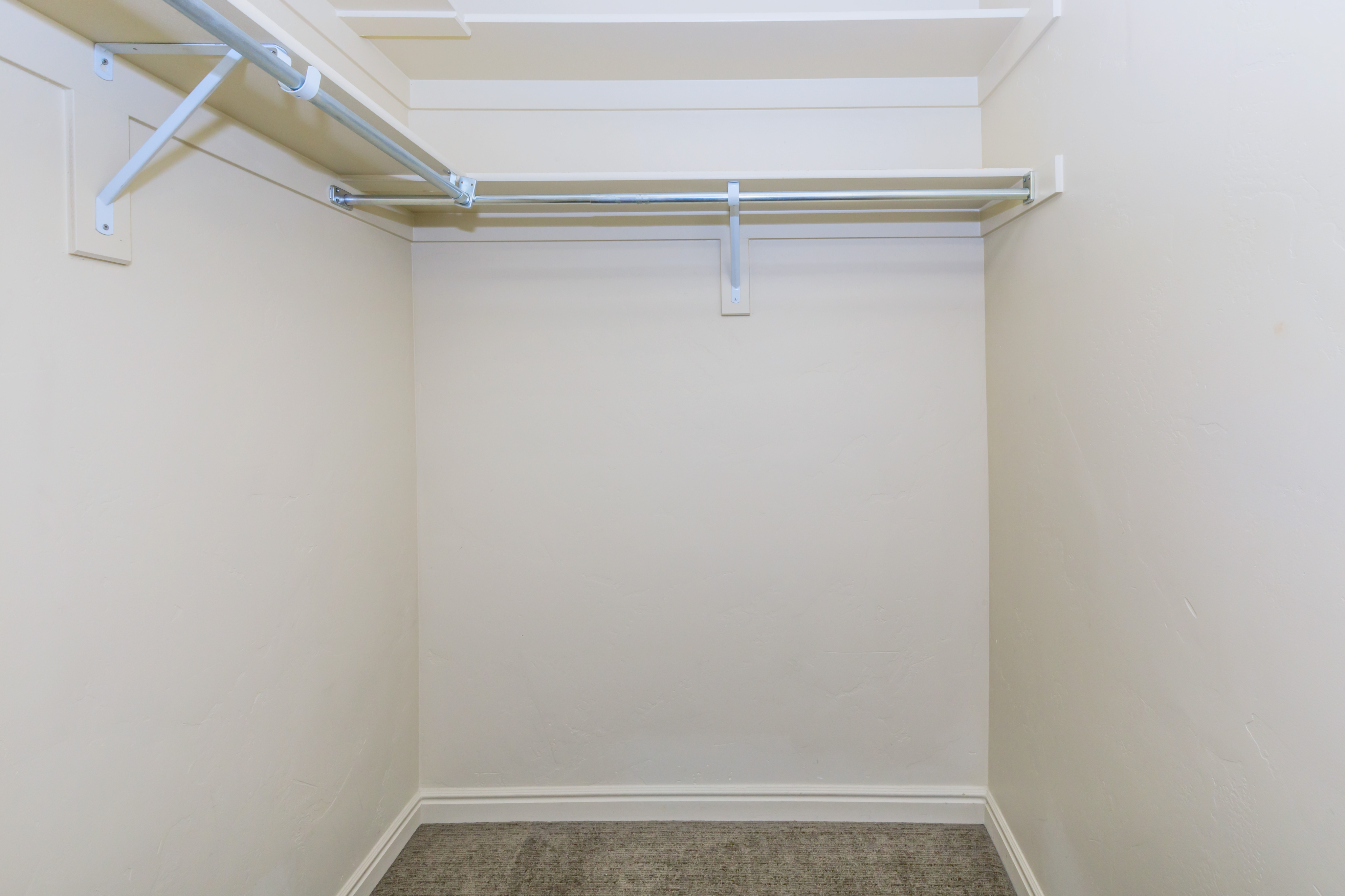 Spacious walk-in closet with clean white walls and ample shelving space, perfect for organized storage solutions.