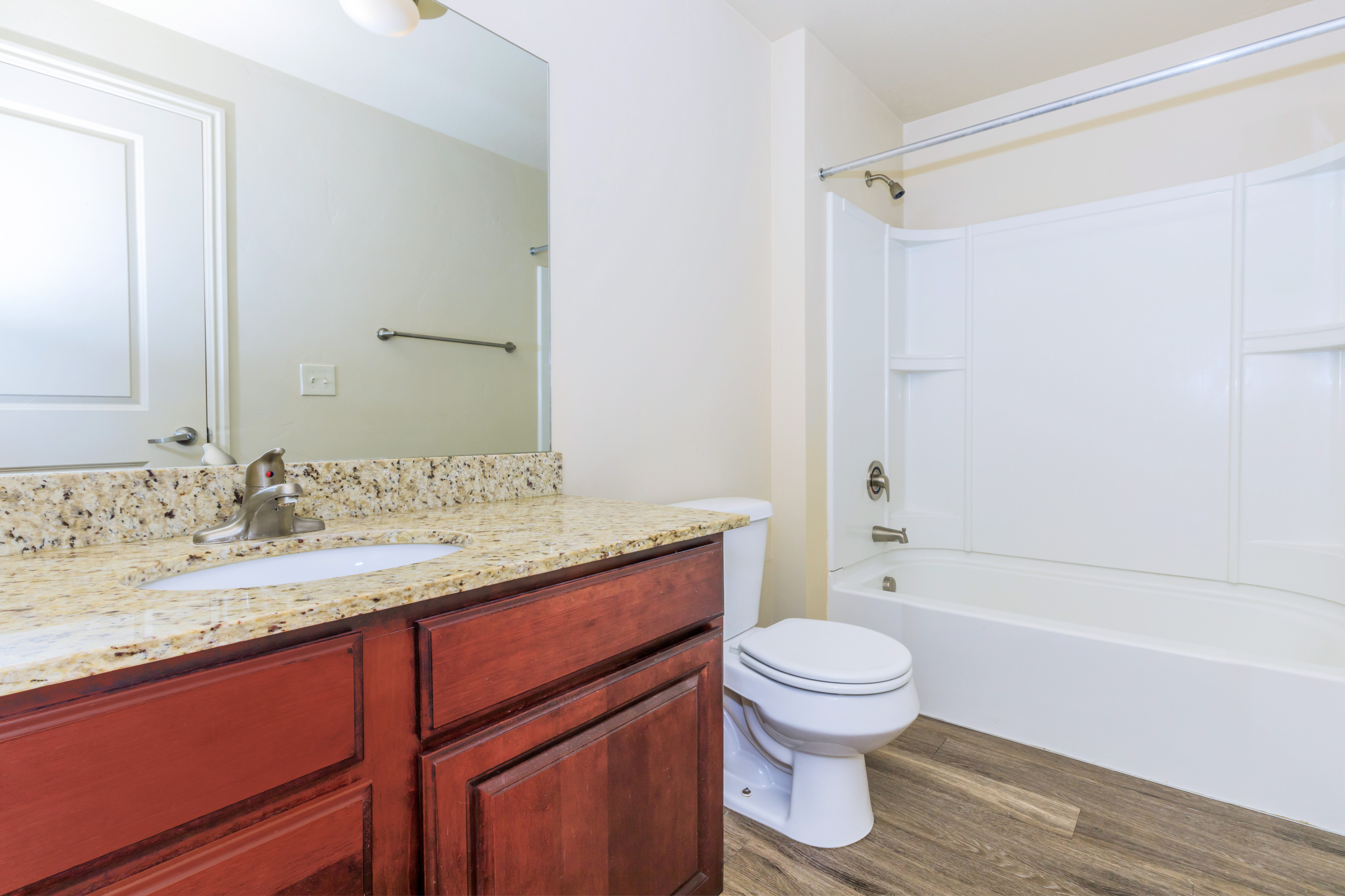Modern bathroom featuring granite countertops, elegant wood cabinetry, and a spacious tub.