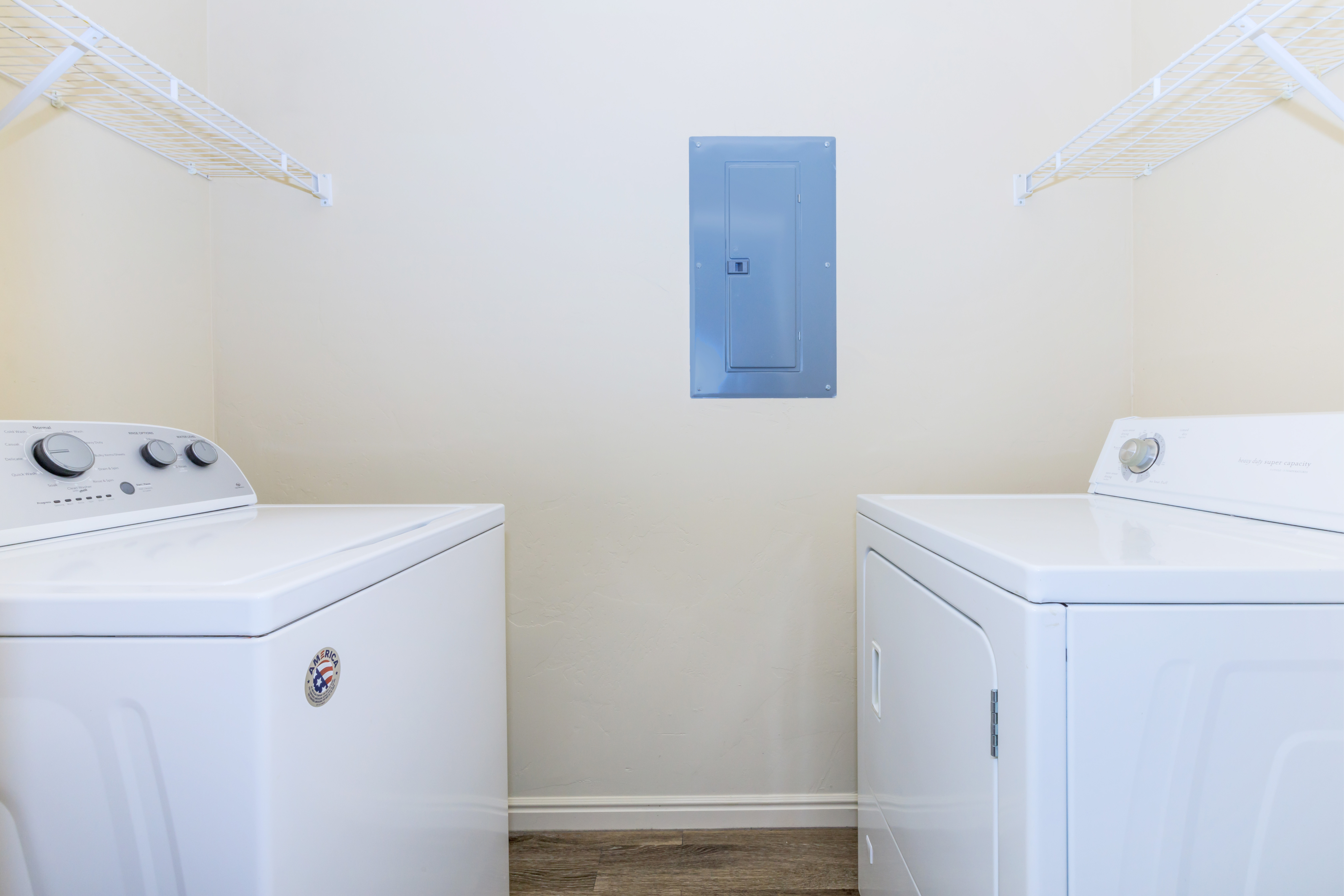 Modern laundry room with top-load washer and dryer, featuring convenient shelving and bright natural light.