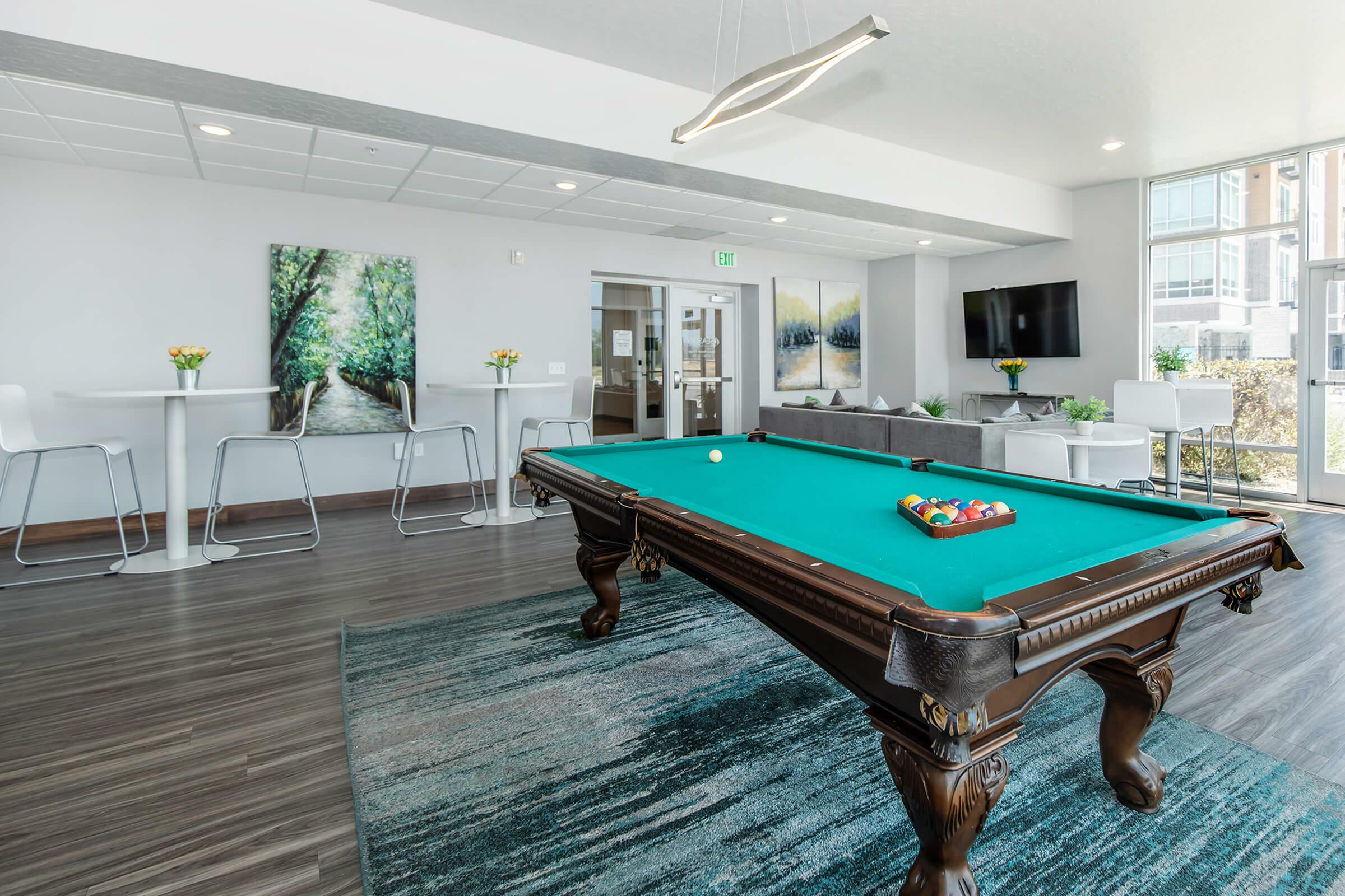 Modern community lounge with stylish pool table, cozy seating, and bright decor, perfect for socializing and relaxation.