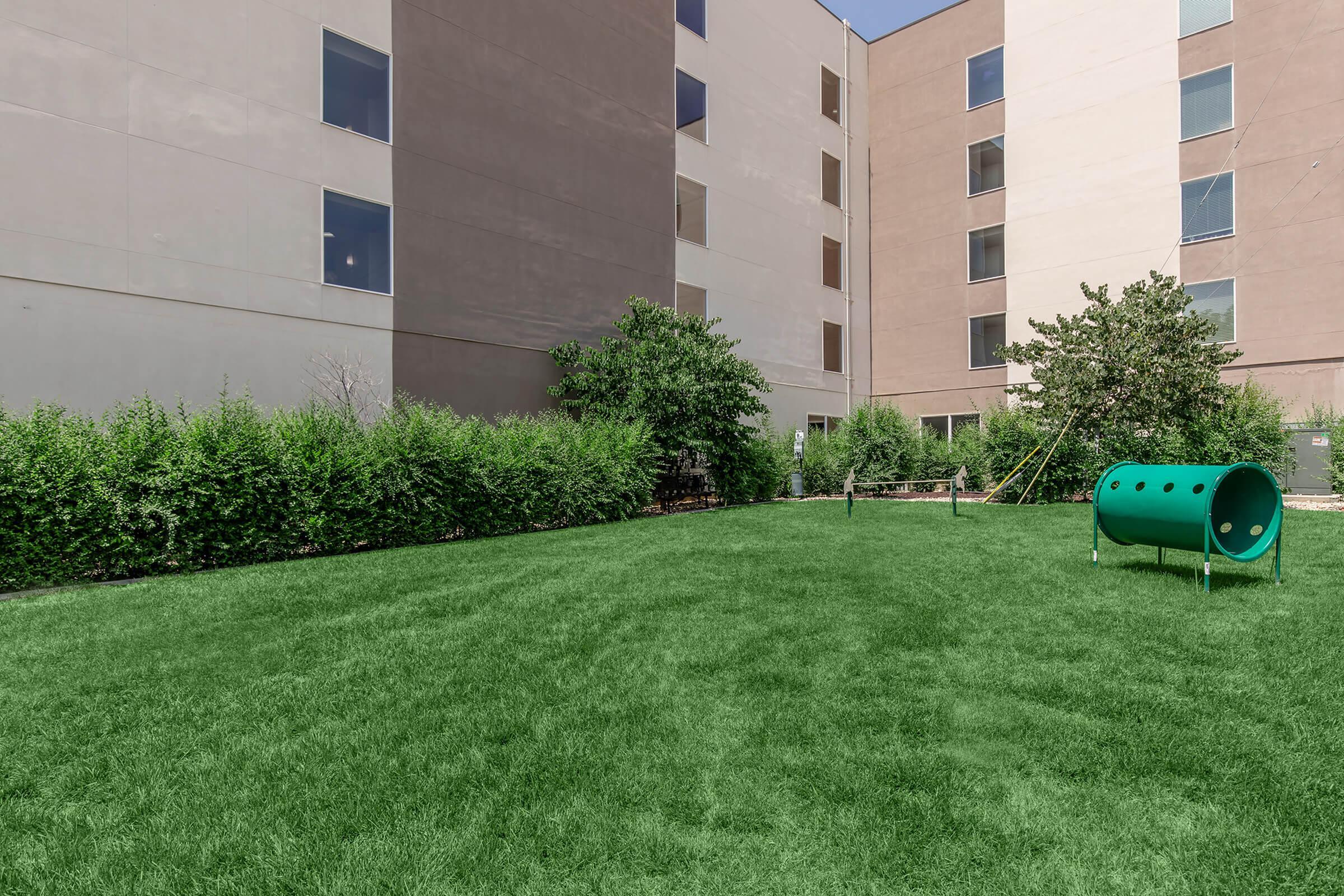 Spacious landscaped courtyard with lush green lawn, surrounded by modern apartment buildings offering a serene outdoor retreat.