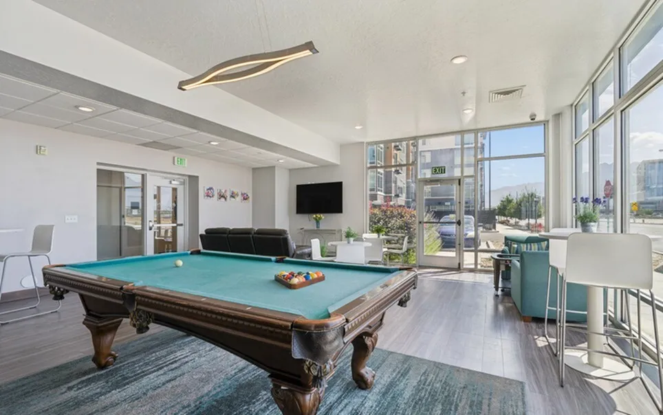 Modern community lounge with stylish pool table, cozy seating, and bright decor, perfect for socializing and relaxation.