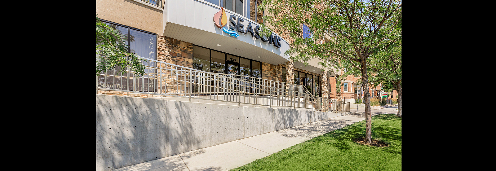 Inviting apartment entrance with modern design, featuring lush landscaping and accessible pathways.