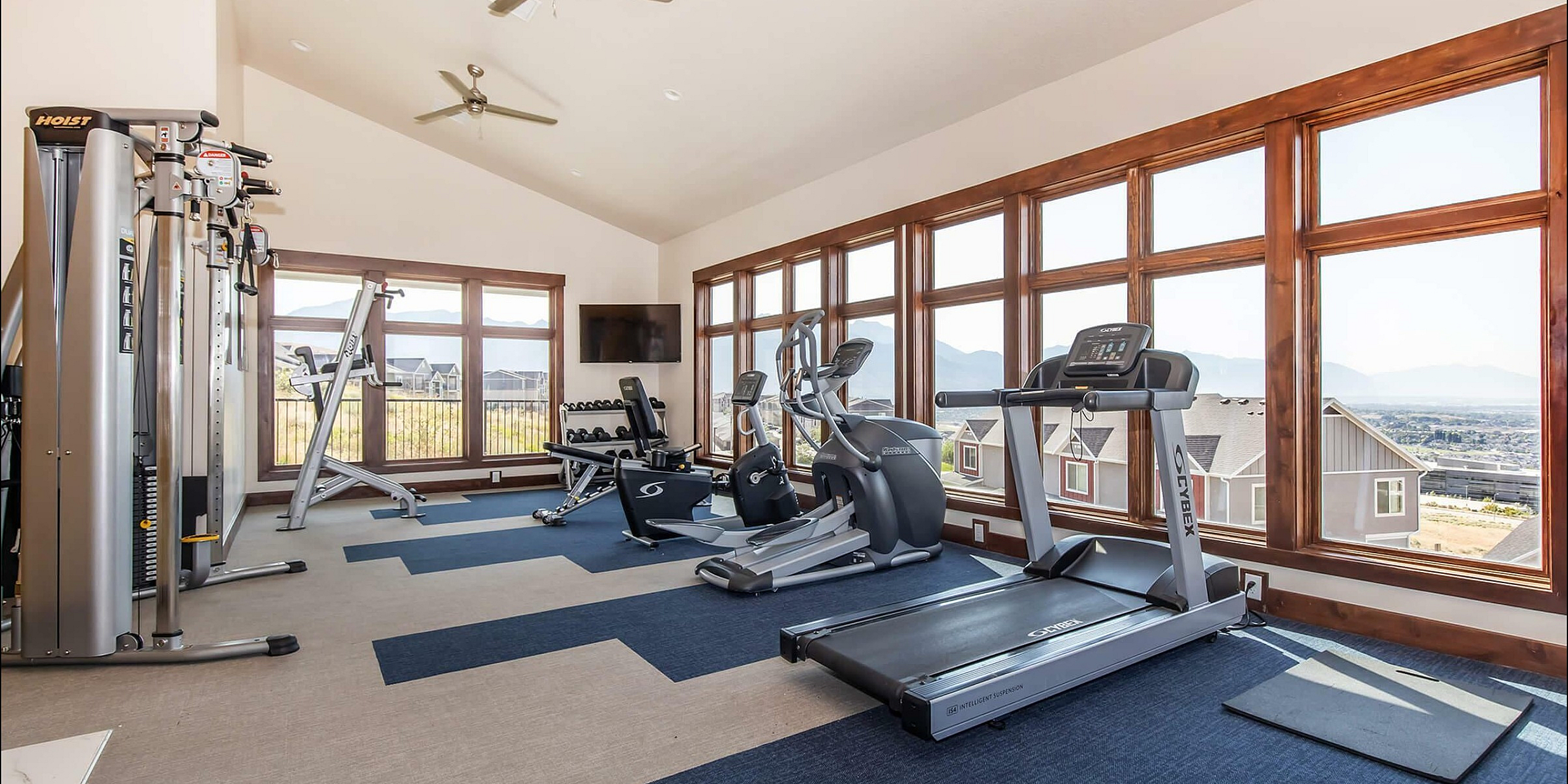 Bright fitness room with modern exercise equipment and large windows offering scenic views.