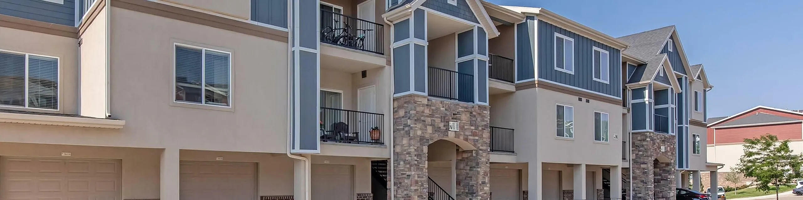 Contemporary apartment complex with stylish stone accents and spacious balconies, offering cozy living spaces and convenient garage parking.