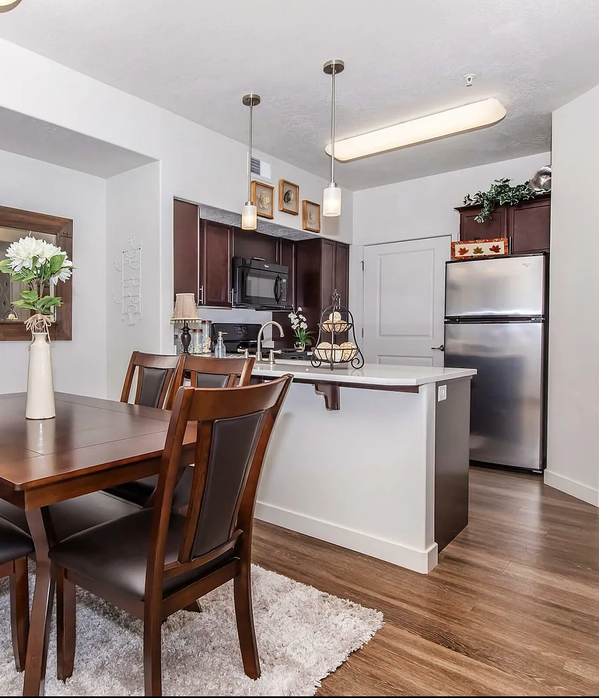 Elegant open dining area with dark wood furniture, stylish kitchen, and modern decor, perfect for intimate gatherings.