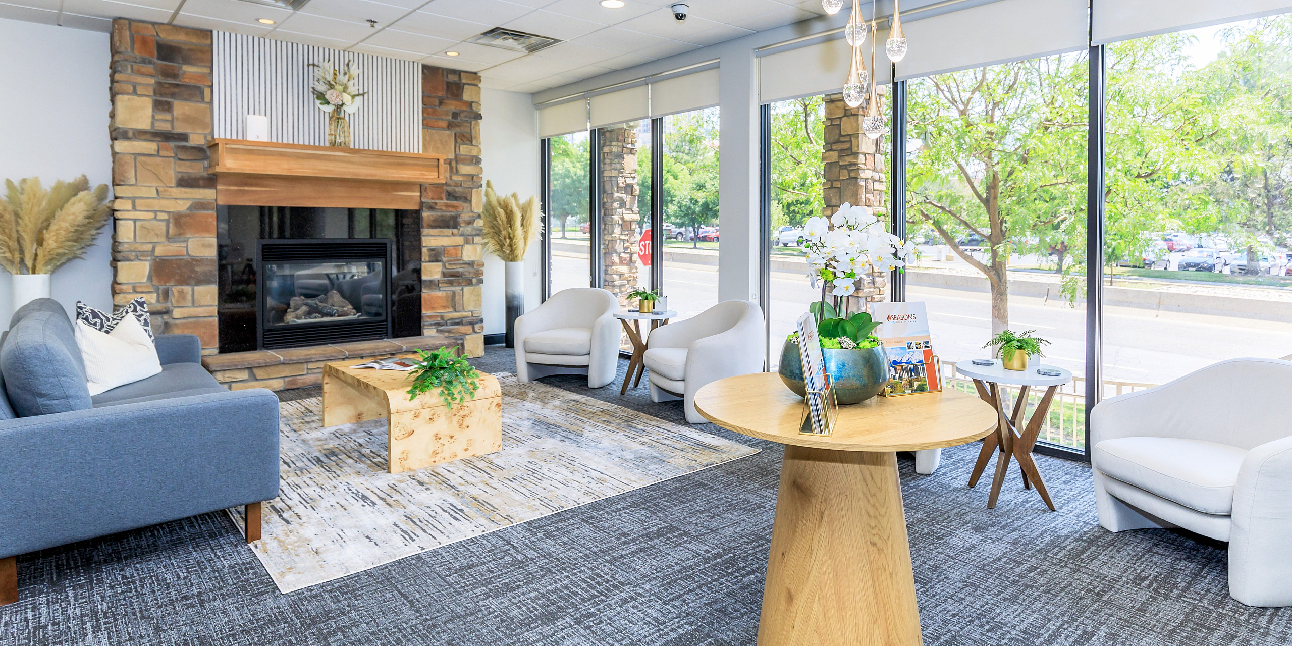 Bright and elegant living space featuring a modern fireplace, stylish seating, and large windows offering scenic views.