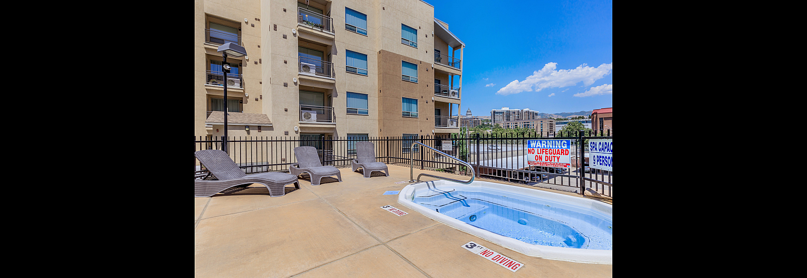 Inviting apartment complex with relaxing outdoor jacuzzi, stylish loungers, and vibrant cityscape views.
