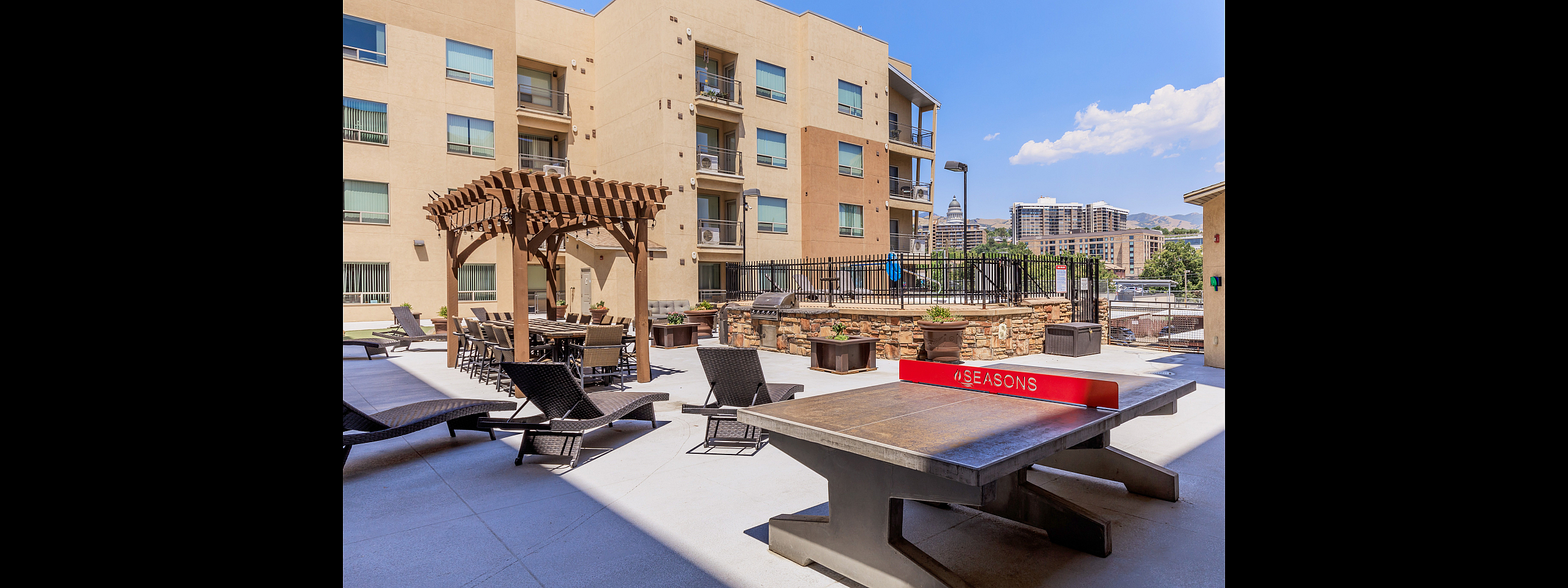 Inviting outdoor patio with cozy seating, modern pergola, and stunning city views set against a vibrant urban backdrop.