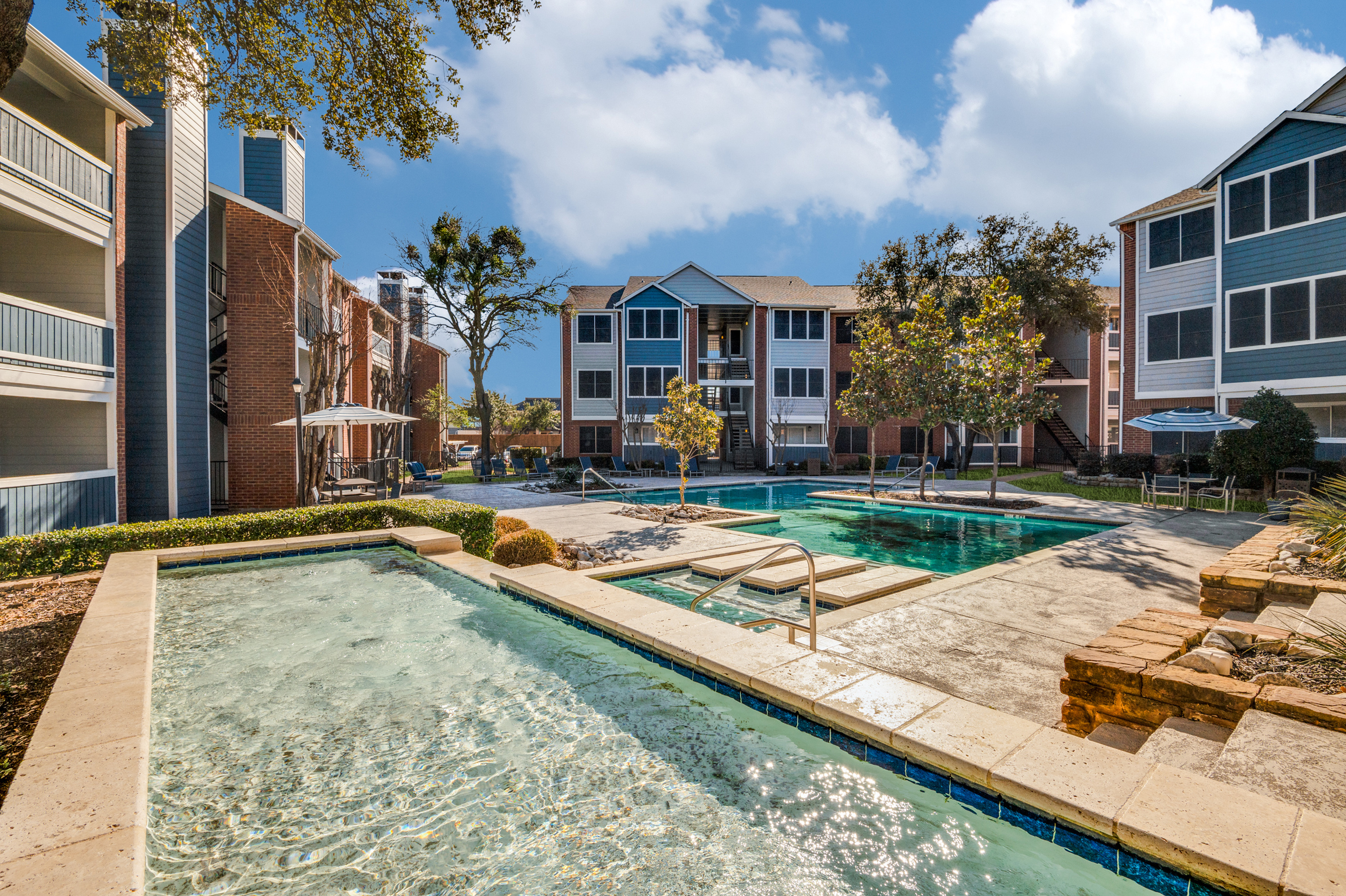 Inviting apartment complex with sparkling swimming pool and lush greenery, perfect for a serene lifestyle.