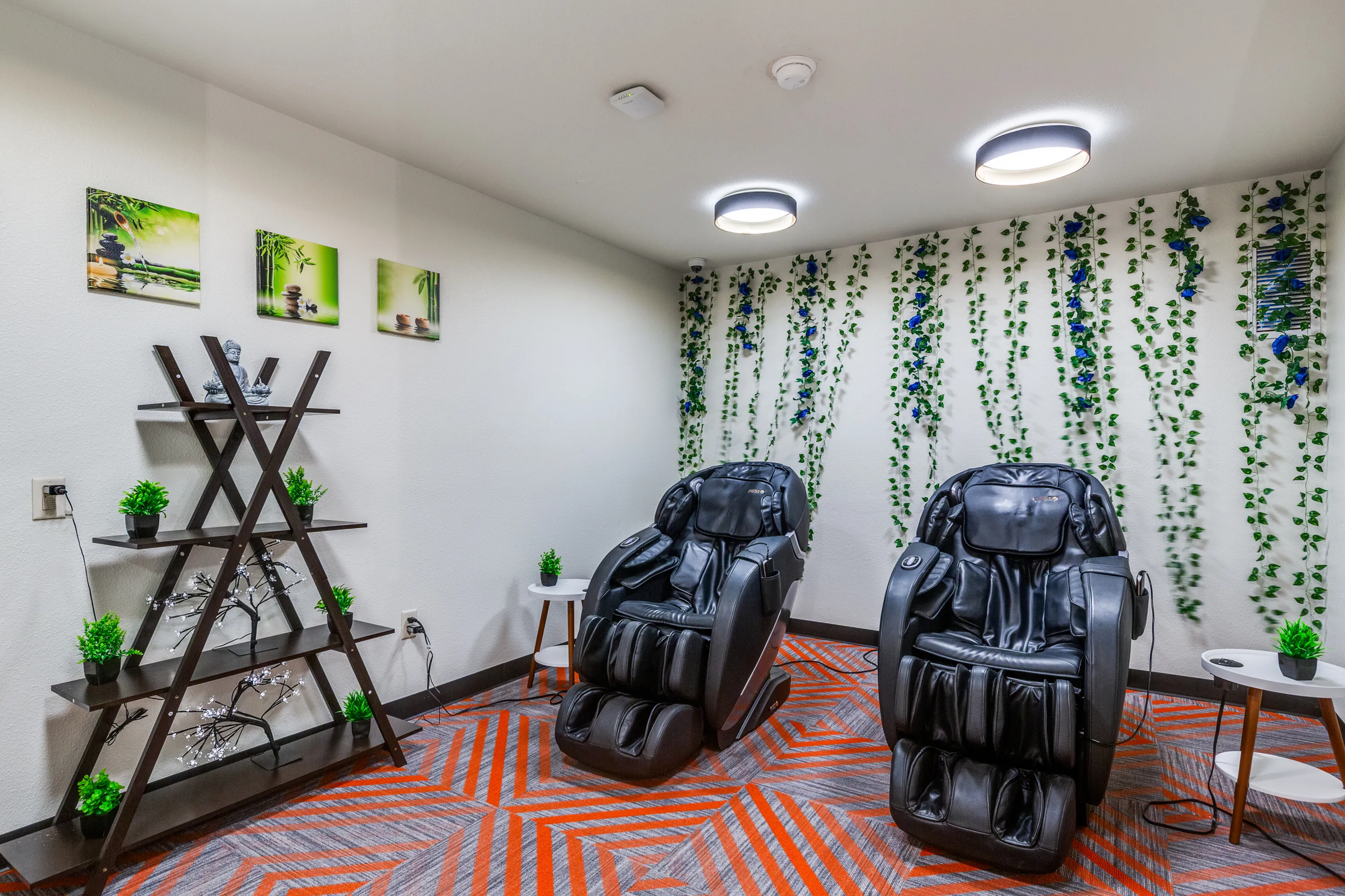 Luxurious relaxation room with two plush massage chairs, ambient wall decor, and vibrant indoor plants for a serene atmosphere.