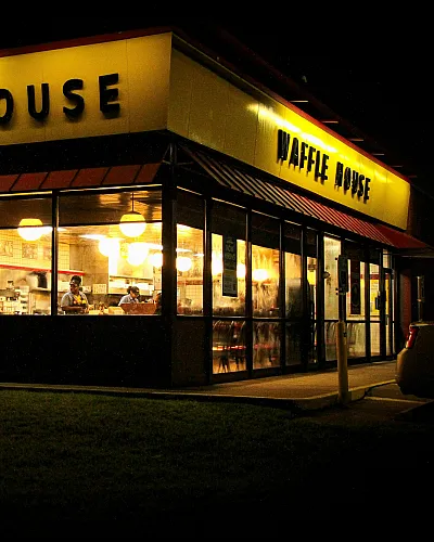Inviting nighttime view of a brightly lit Waffle House with a cozy atmosphere, showcasing the classic American diner experience.