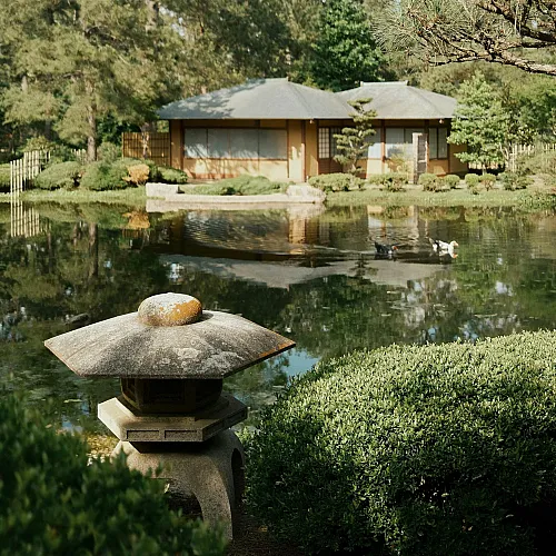 Tranquil Japanese-style garden with a traditional house by a serene pond, surrounded by lush greenery and pine trees.