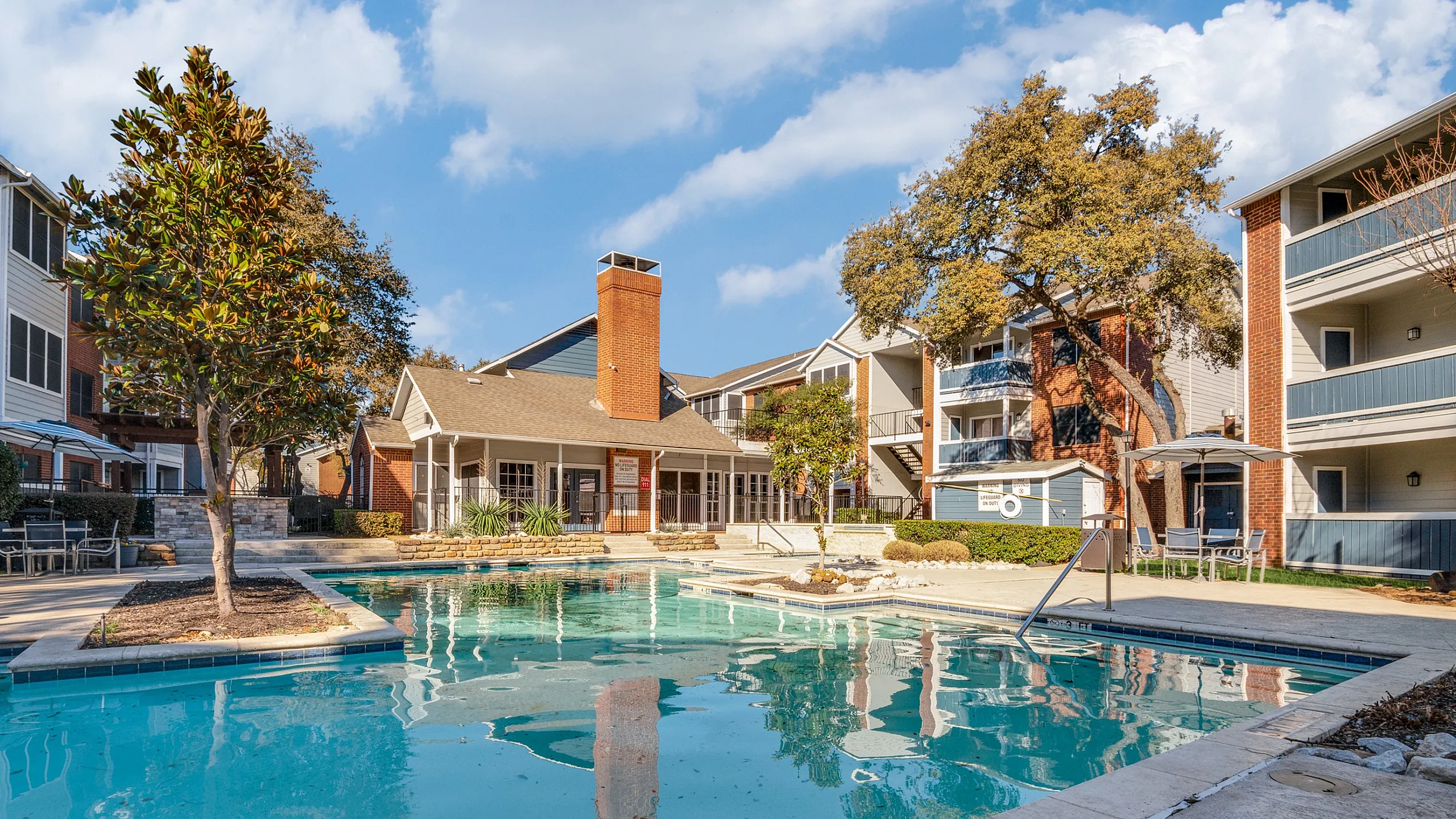Inviting apartment complex with a sparkling pool surrounded by lush greenery and stylish architecture, perfect for relaxation and leisure.