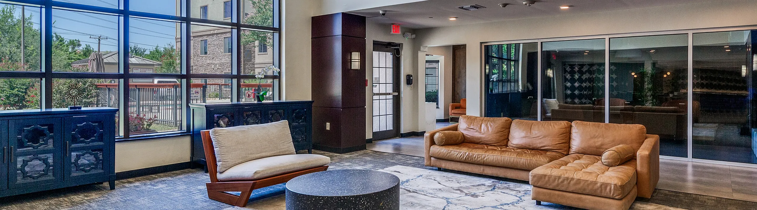 Bright and modern apartment lounge with stylish leather sofas, expansive windows, and contemporary decor.