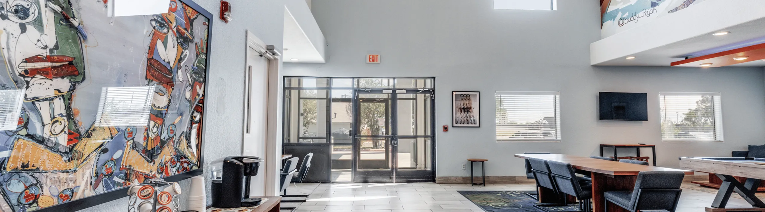 Modern apartment lobby with vibrant artwork, sleek furnishings, natural light, and a welcoming atmosphere.