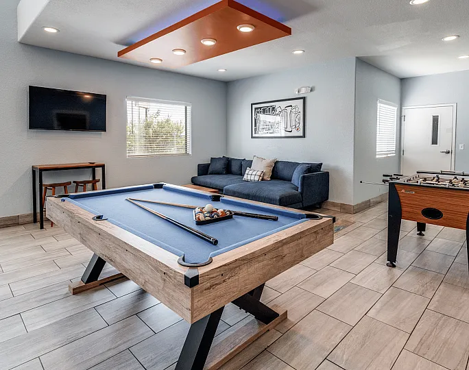 Chic recreational room featuring a sleek pool table, modern foosball game, comfortable seating area, and stylish decor.