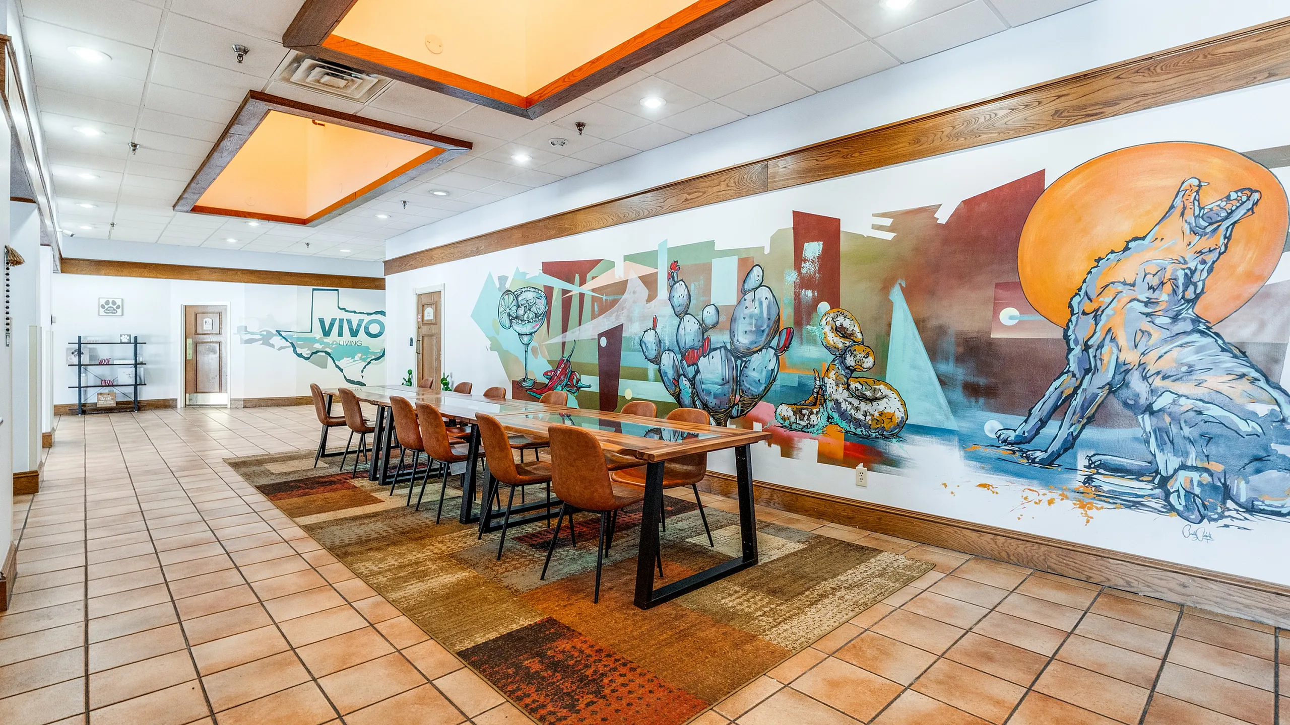 Vibrant community space featuring modern artwork, a spacious wooden table, and warm ambient lighting.