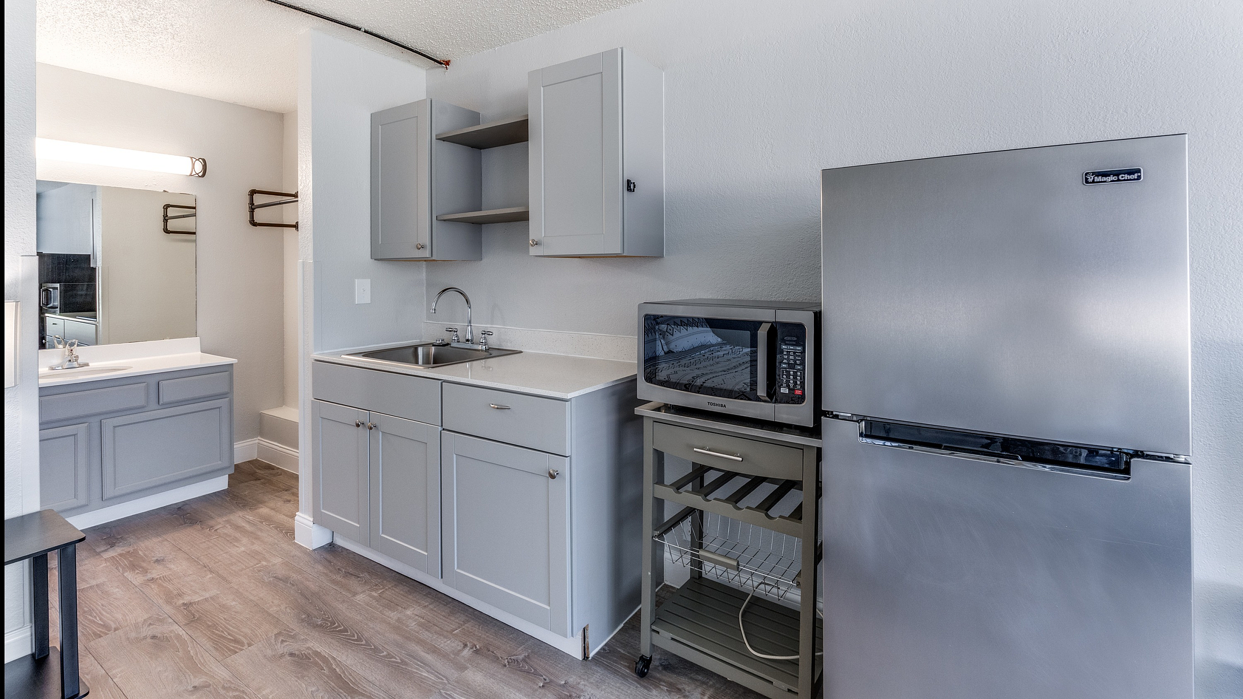 Modern kitchenette featuring sleek gray cabinets, a compact sink, and stainless steel appliances for convenient cooking.